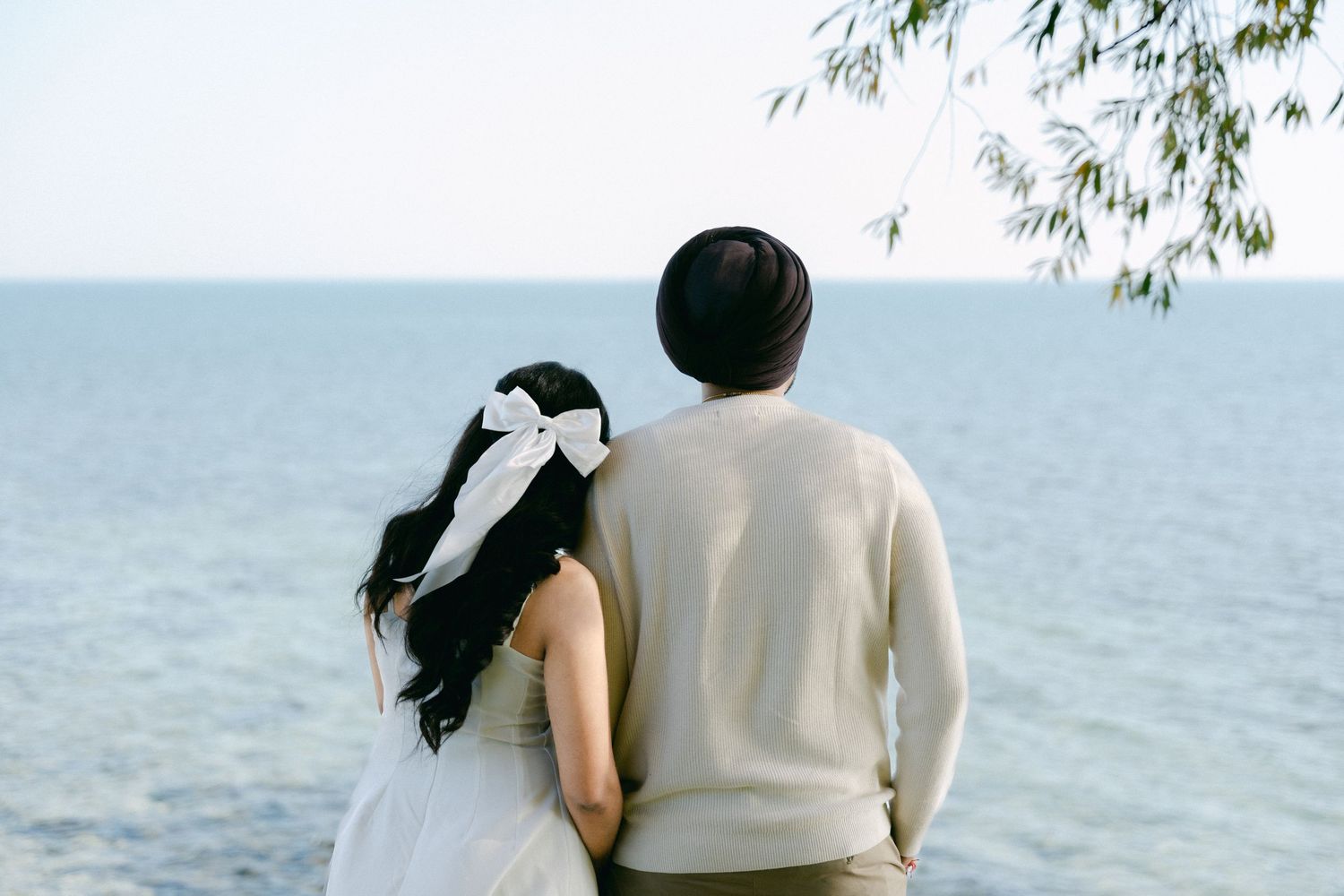 A couple in romantic attire gazes at the ocean view together on a peaceful afternoon.