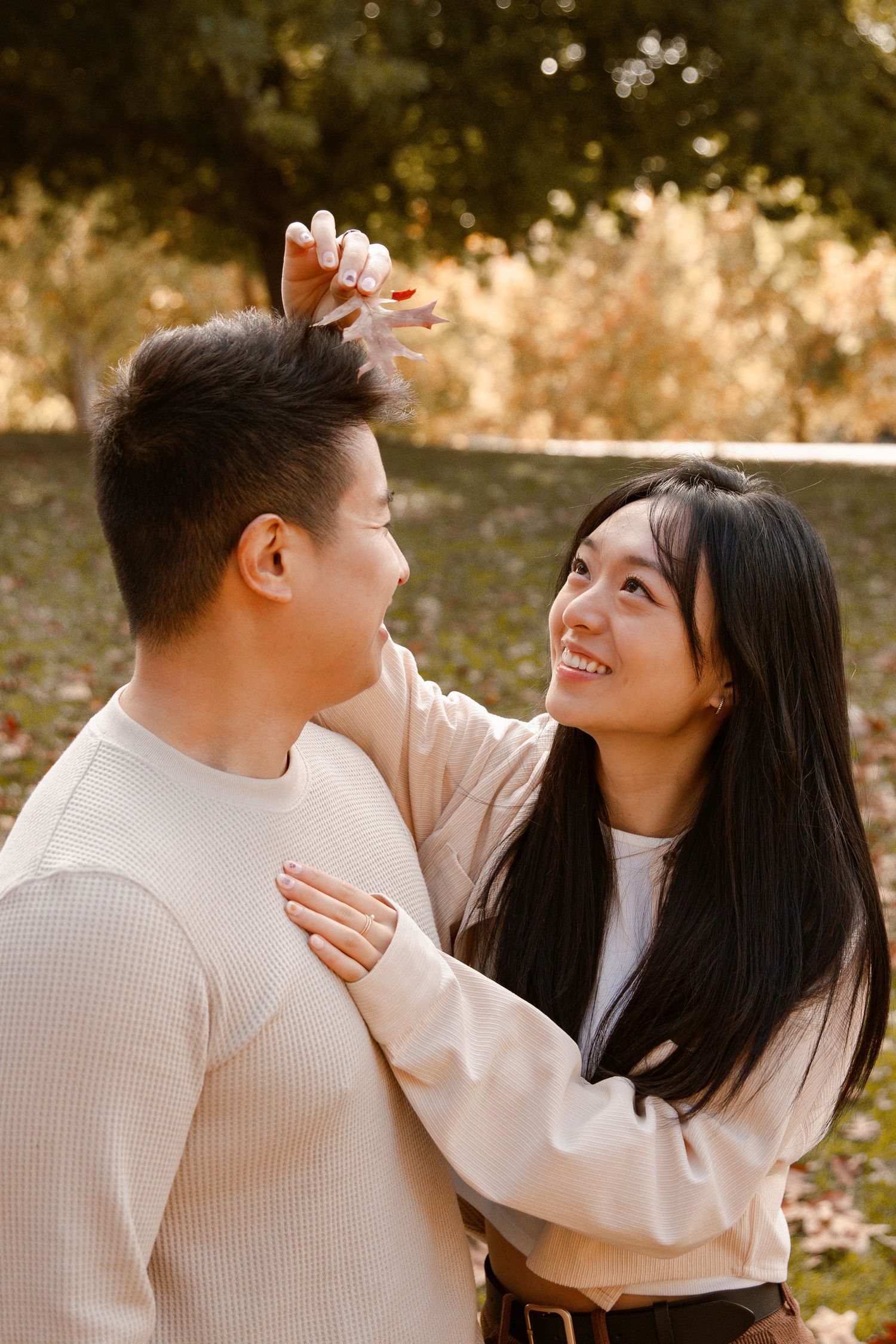 Romantic couple sharing intimate moment outdoors in autumn sunlight.