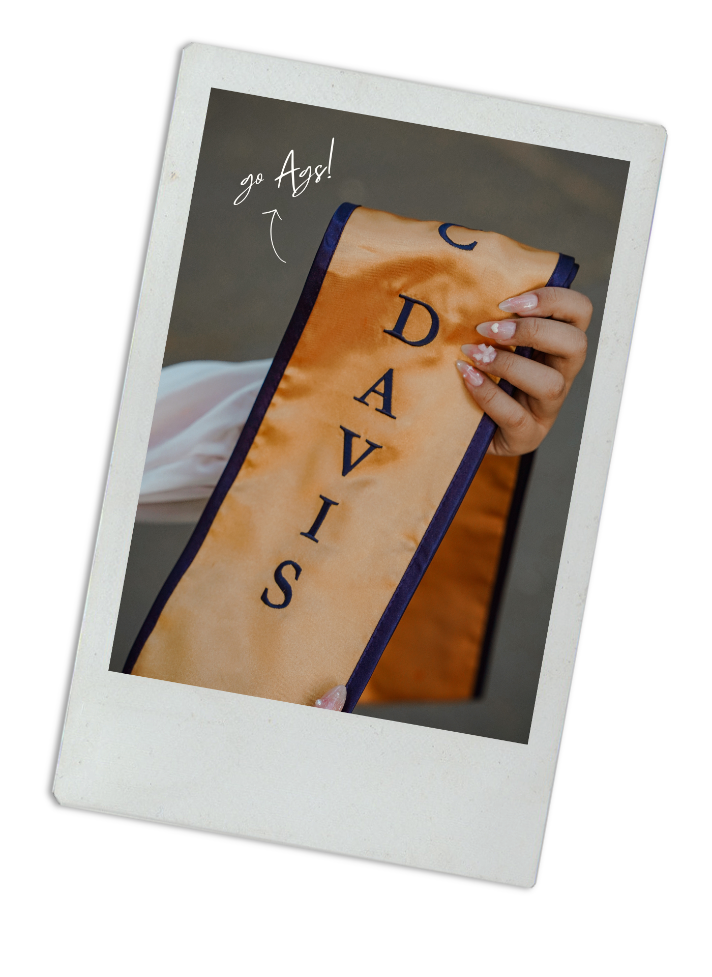 Close-up Polaroid photo of UC Davis graduation sash with blue trim.
