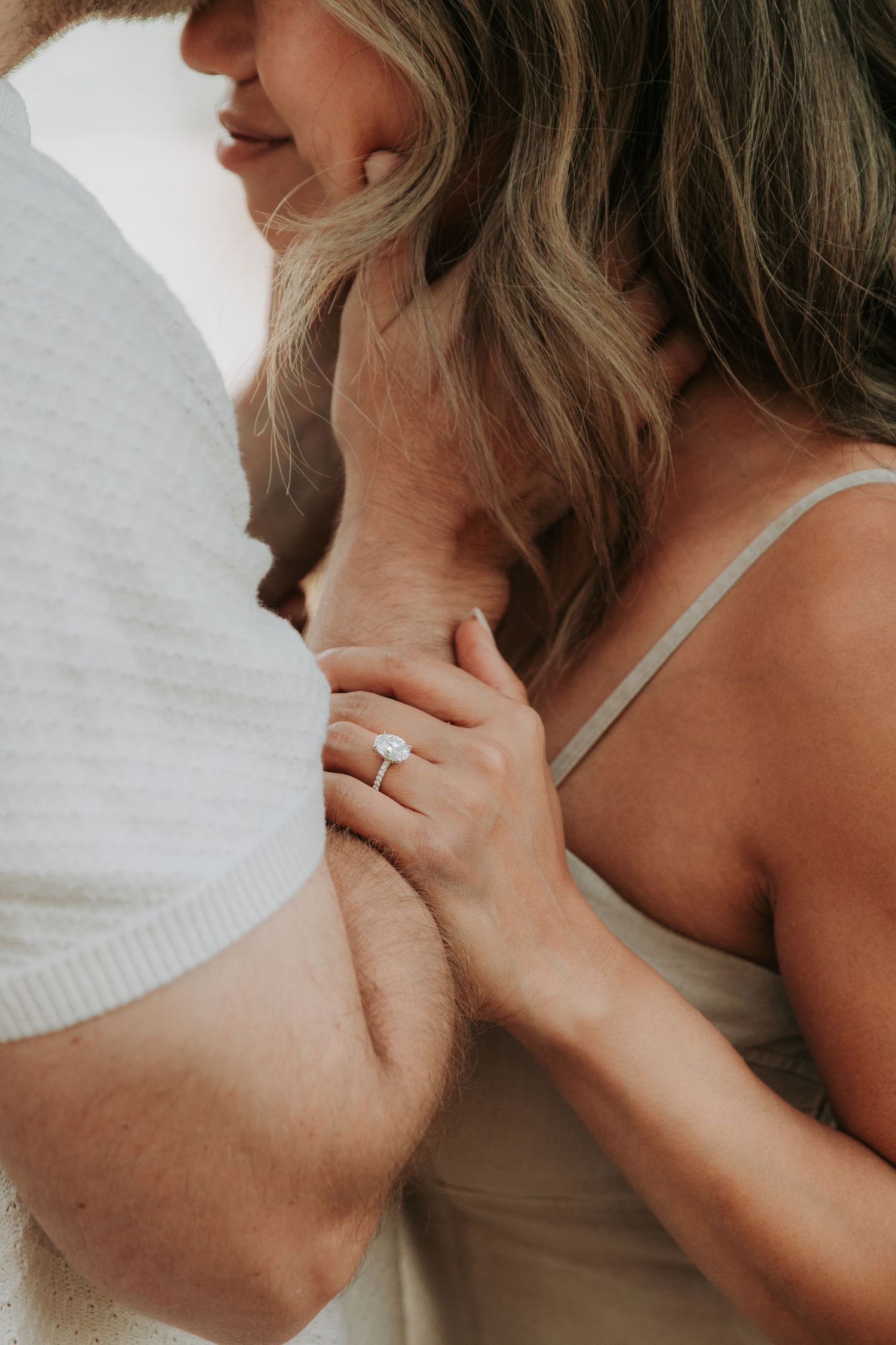 Close-up intimate moment showing hands, wedding ring and tender embrace in soft natural lighting.
