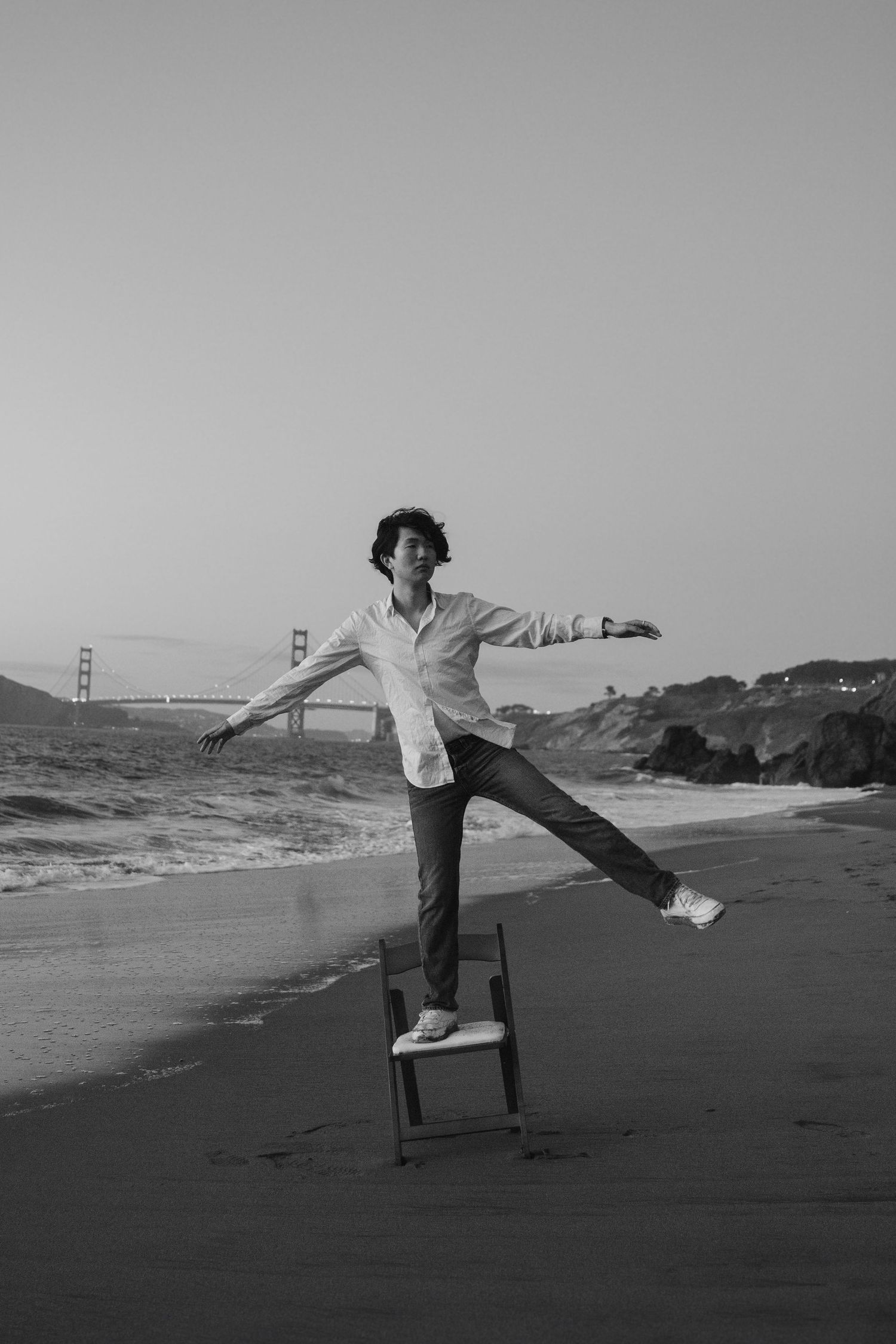 Artistic black and white shot of someone performing a balance pose on a beach chair.