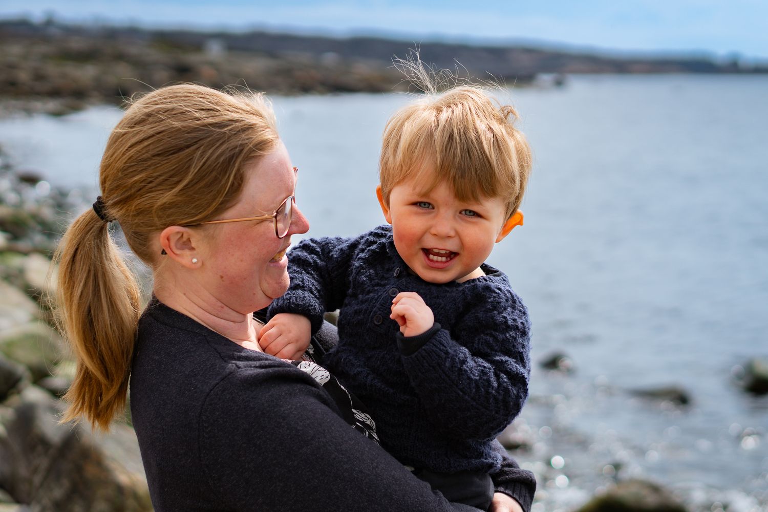 Kärleksfull stund med glädje där en mamma håller sin son i famnen vid havet. Familjefotograf, Umeå, Västerbotten