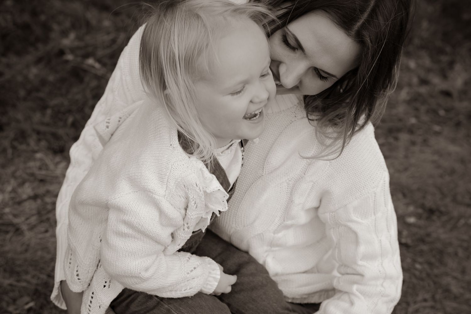 Svartvit bild på mamma med dotter i knät där båda skrattar varmt. Fotograf, familjefotograf, Umeå, Västerbotten