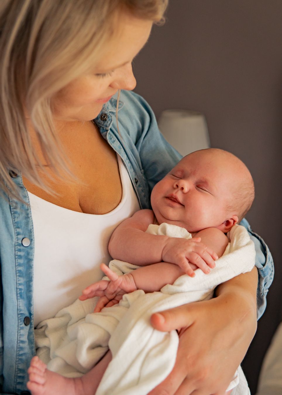 Ett fridfullt ögonblick när en bebis vilar i mammas famn, hon är klädd i denim. Fotograf, Familjefotograf, Familjefotografering, Umeå