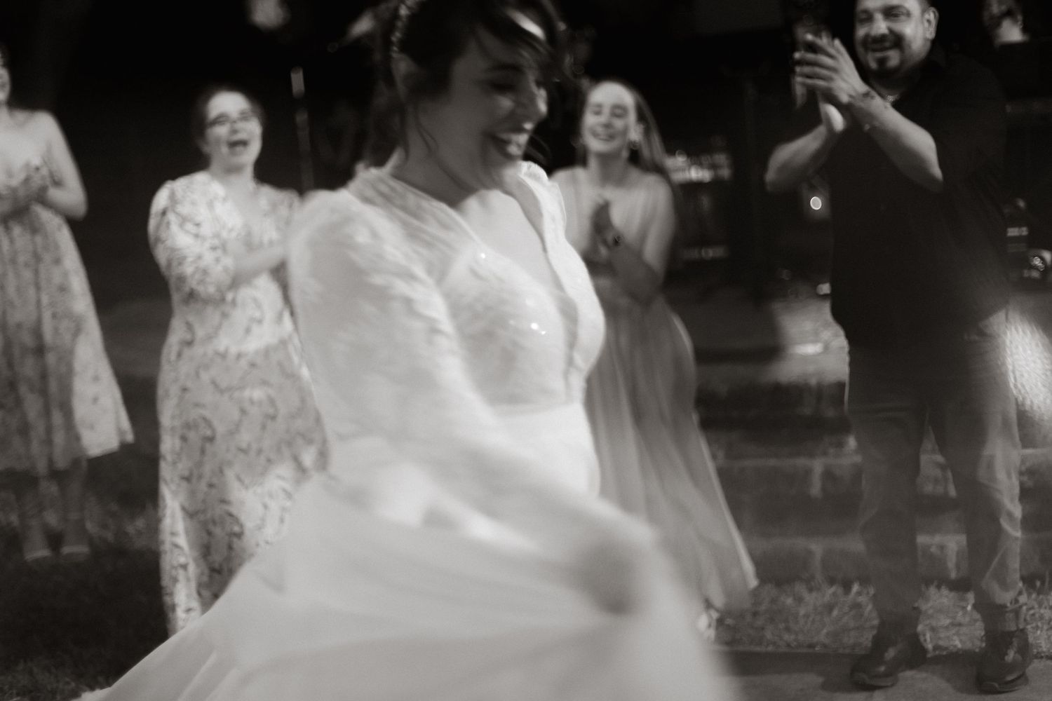 Couple enjoying their first dance at a wedding reception with guests watching and clapping in the background.