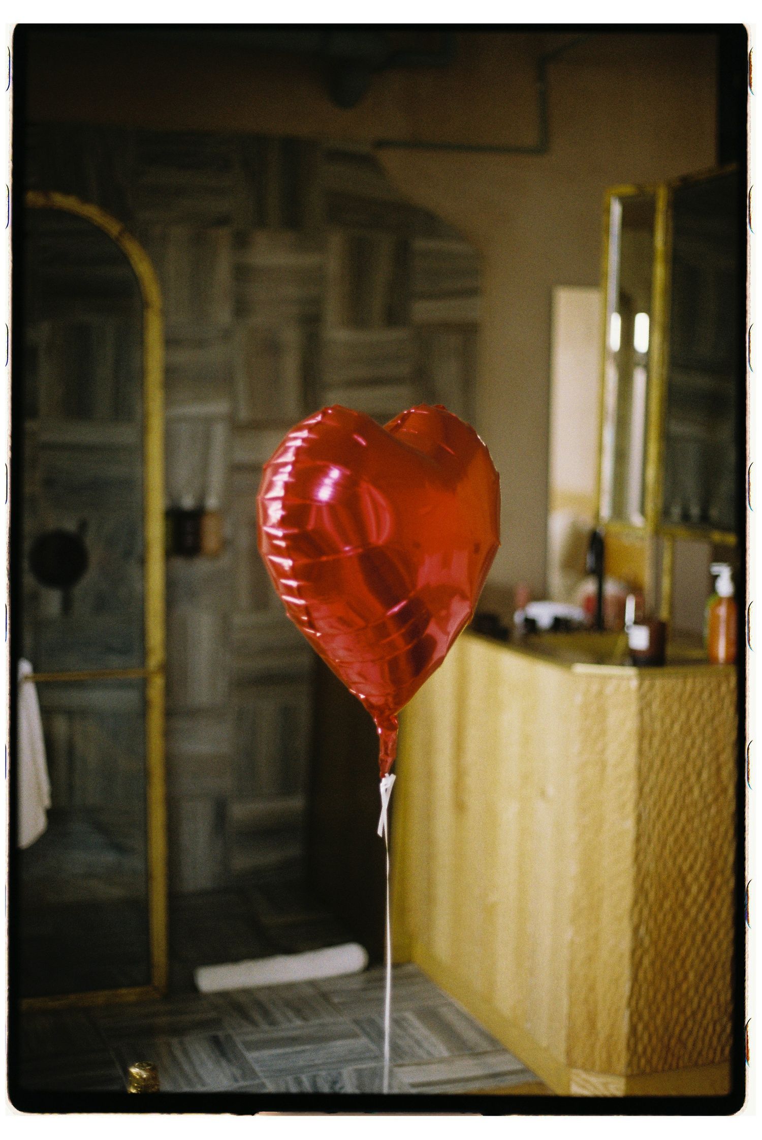 A series of four blurry photos showing red heart-shaped balloons in a dimly lit indoor space or hallway.