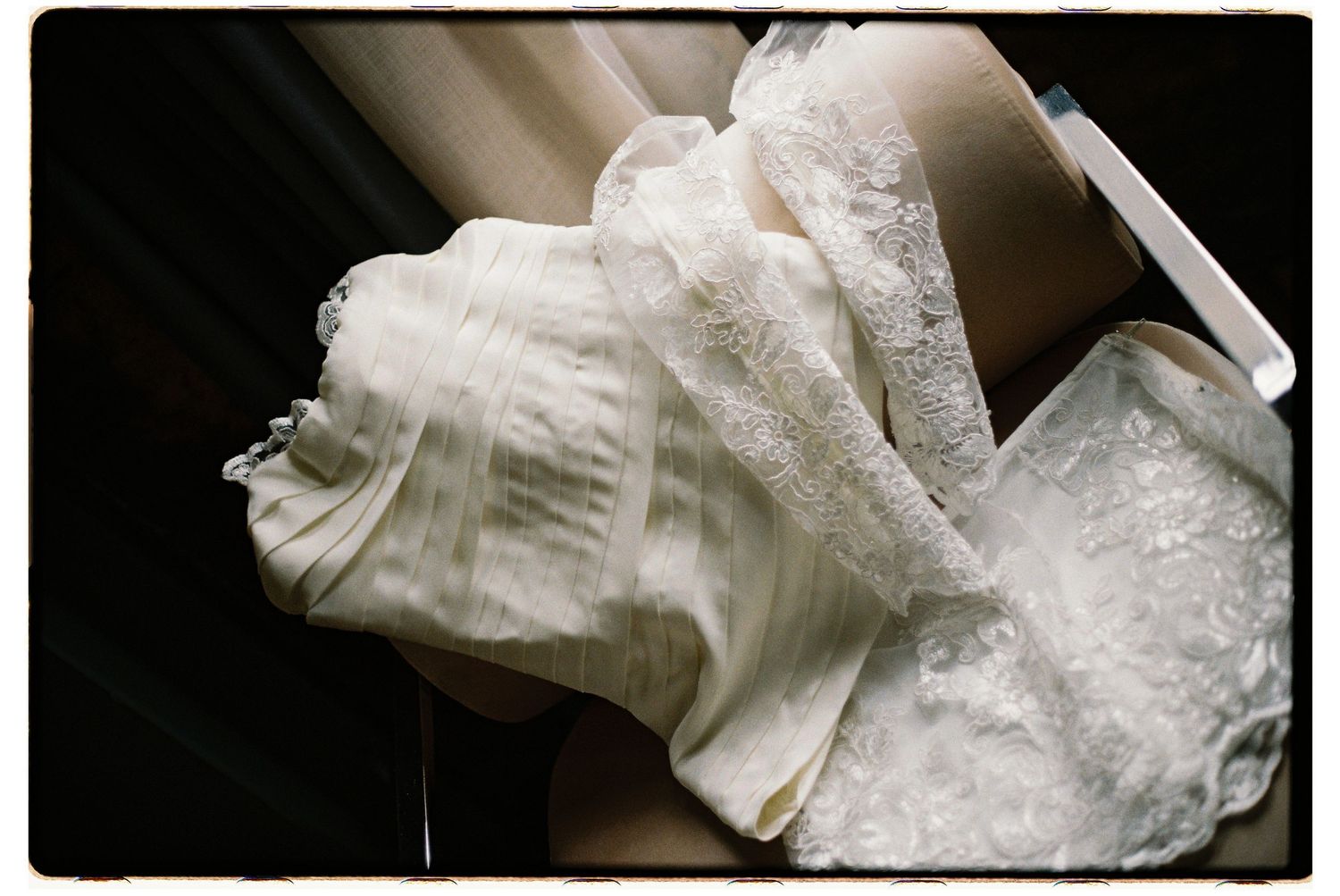 A delicate white lace and tulle wedding dress folded and displayed in soft lighting.