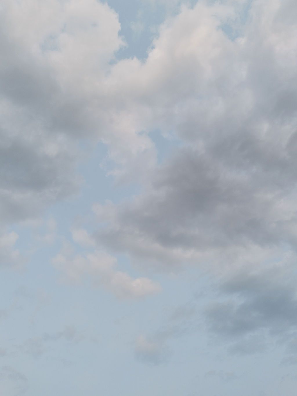Wispy gray and white clouds float across a pale blue sky creating a dreamy atmospheric backdrop.
