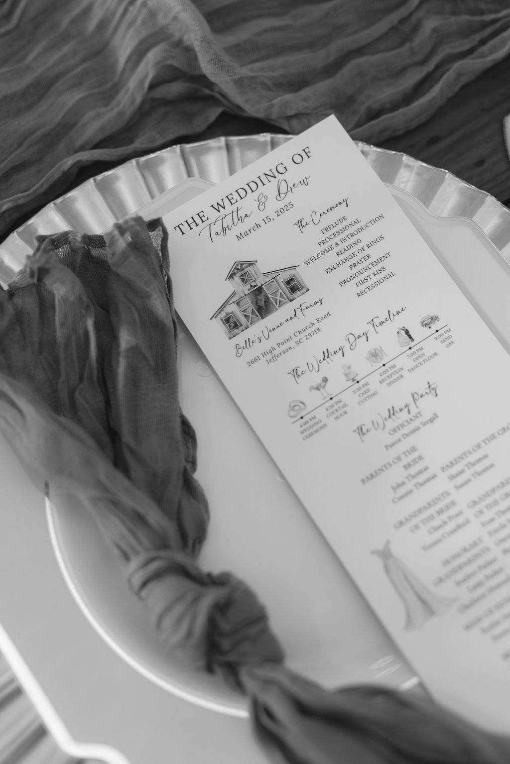 A black and white photograph of an elegant wedding program with a church illustration resting on a white plate.