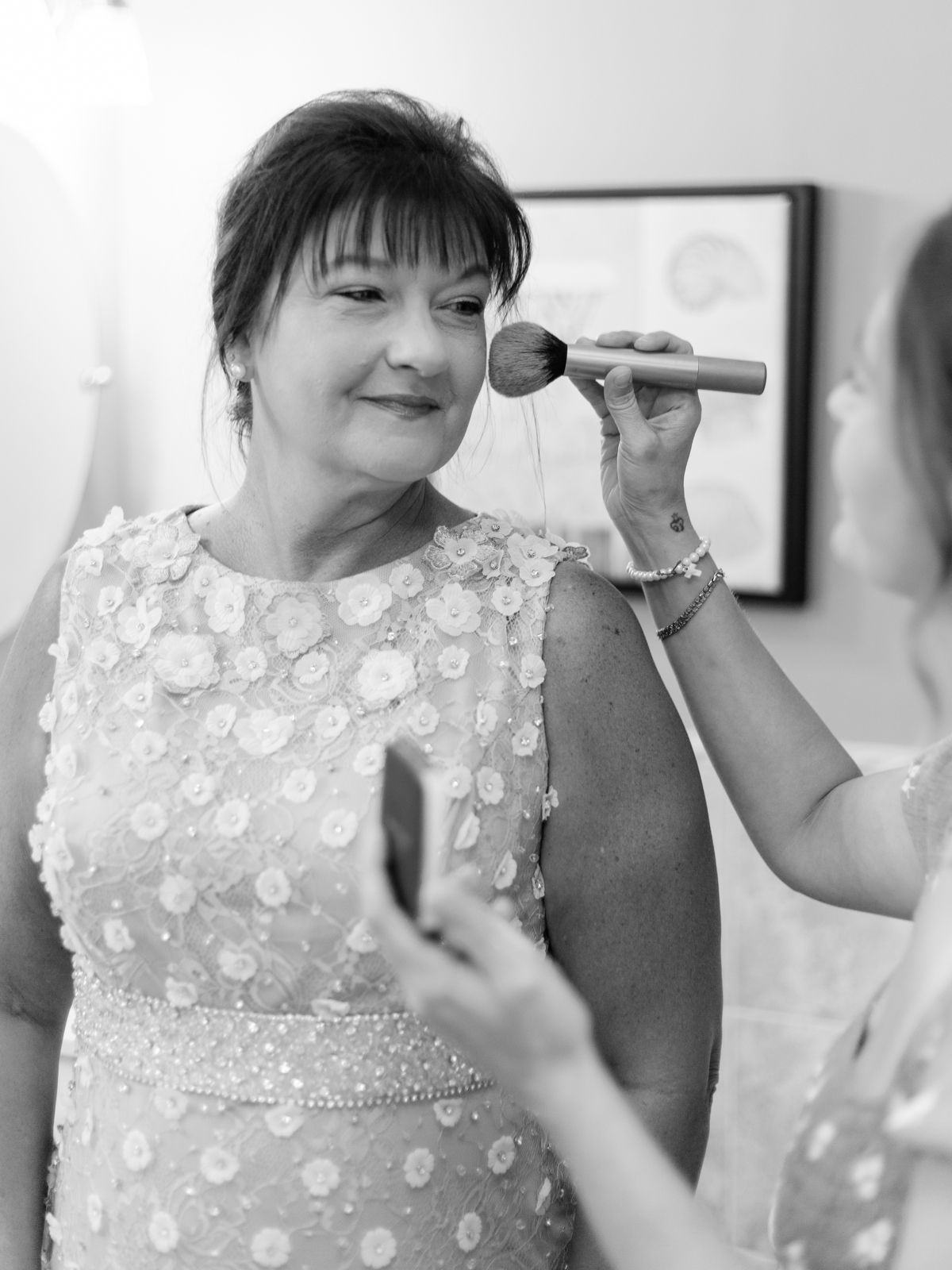 Person having makeup applied while wearing a beaded white formal dress.