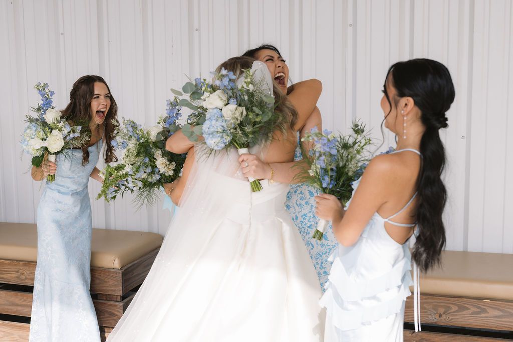 Three people in light blue bridesmaid dresses and white face masks hold floral bouquets with eucalyptus and white flowers.