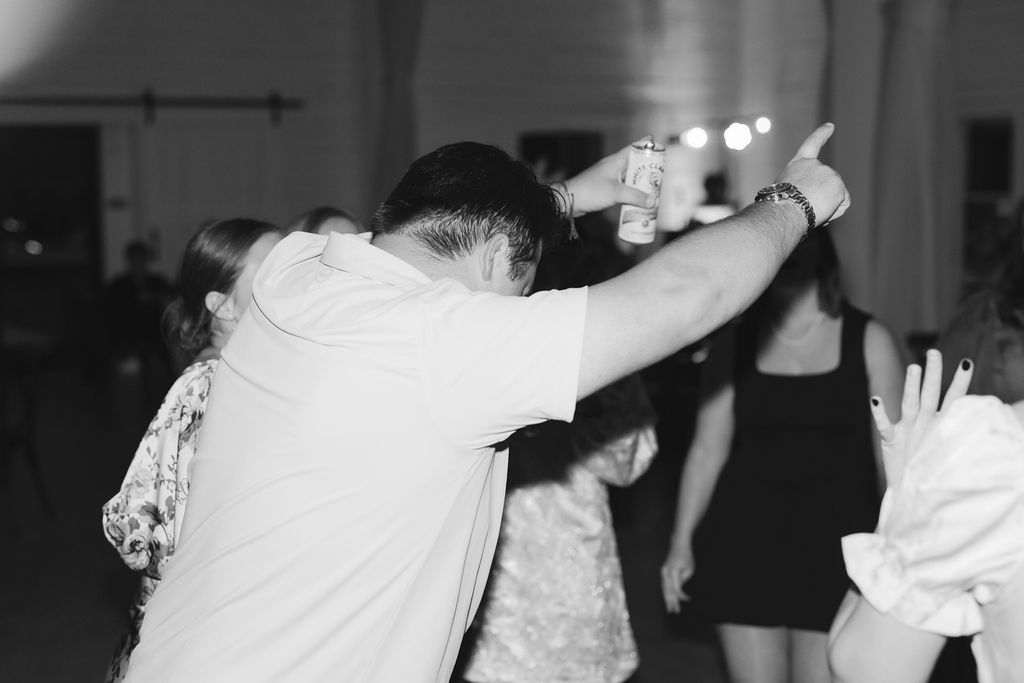 Black and white photo of people dancing at a celebration, with hands raised in joyful motion.