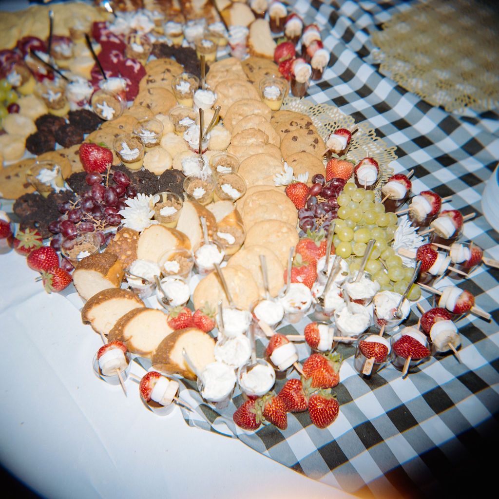 A platter of catered appetizers with mushrooms, cheese, and fruit arranged on a checkered tablecloth.