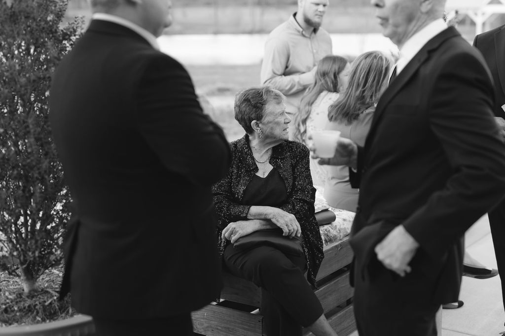 A black and white vintage photograph showing people gathered in conversation outdoors.