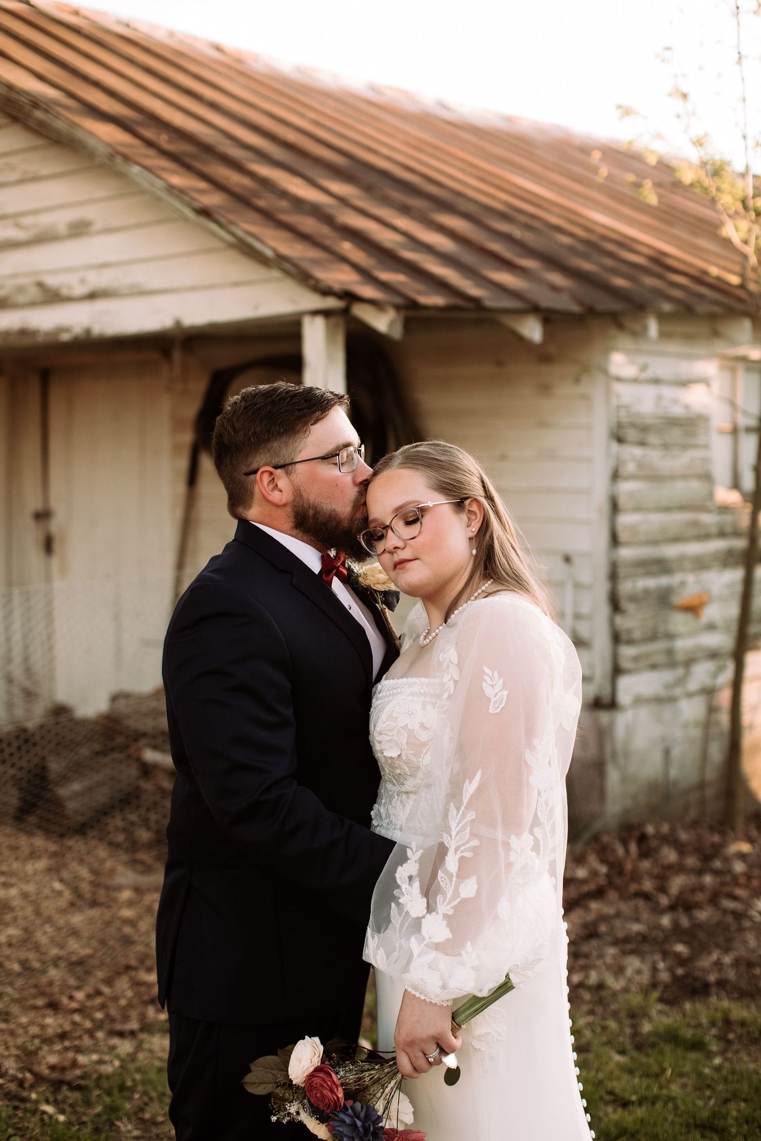 A romantic couple in wedding attire shares intimate moments in front of a rustic building during golden hour.