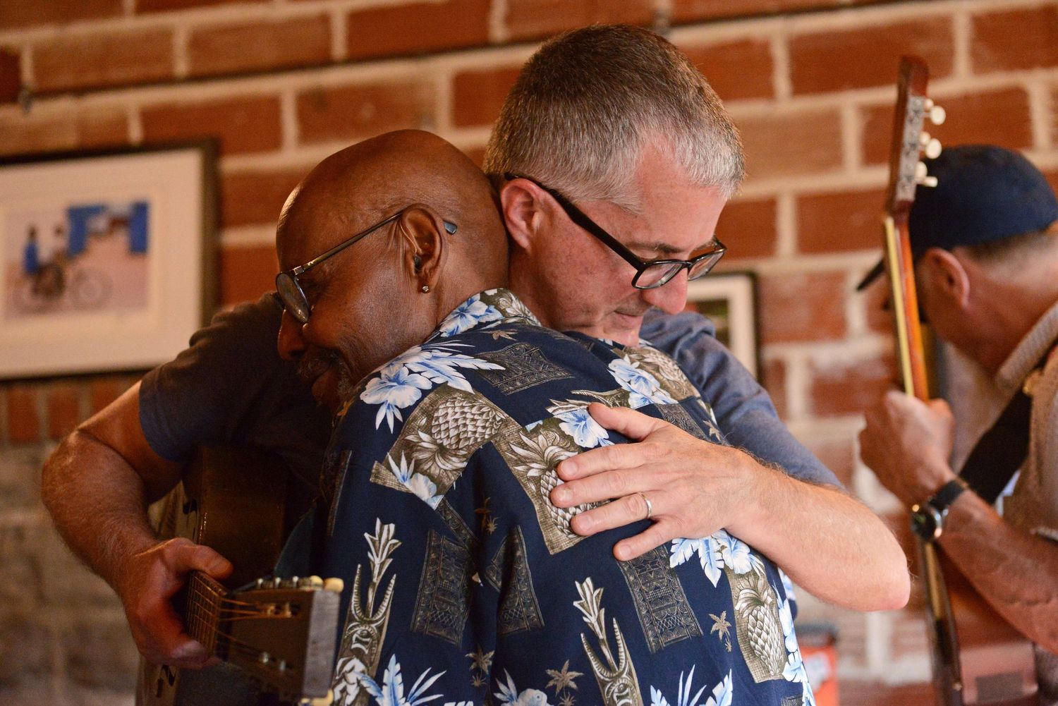 Dave Angle, right, embraces Kenny Greene after he came to watch Angle’s performance on Friday at ARTlandish Gallery in Columbia.