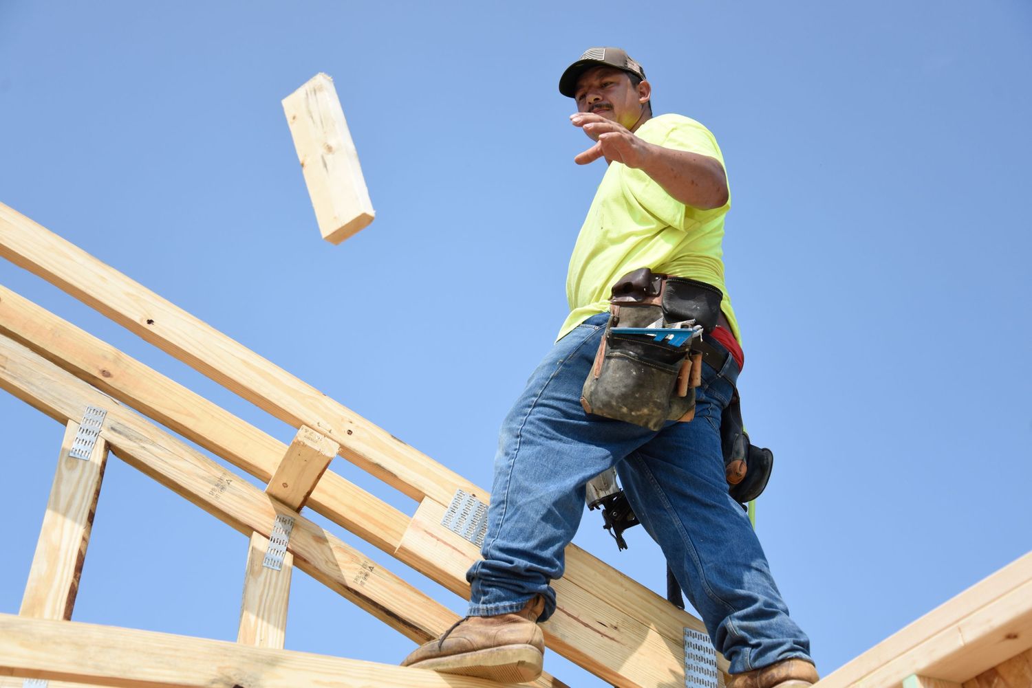 Sergio Cubas catches a piece of wood thrown to him by one of the other volunteer framers.