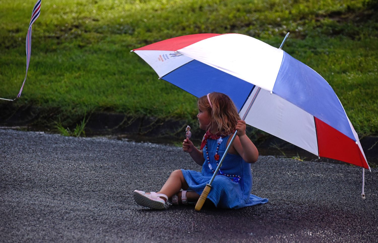 A girl sits under an umbrella to stay hidden from the rain during the parade.