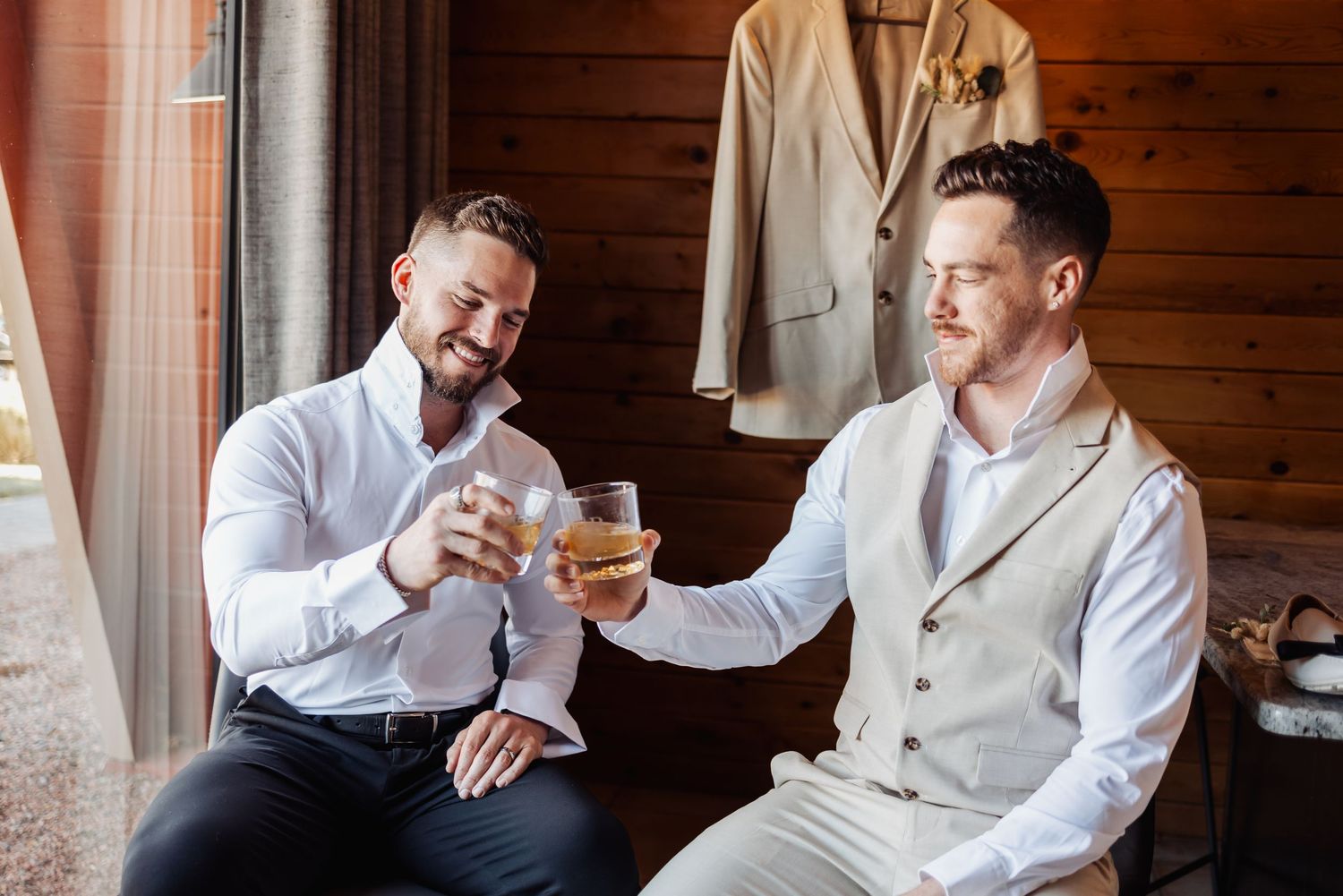 Group of people in white dress shirts smiling and sharing drinks while getting ready in wood paneled room.