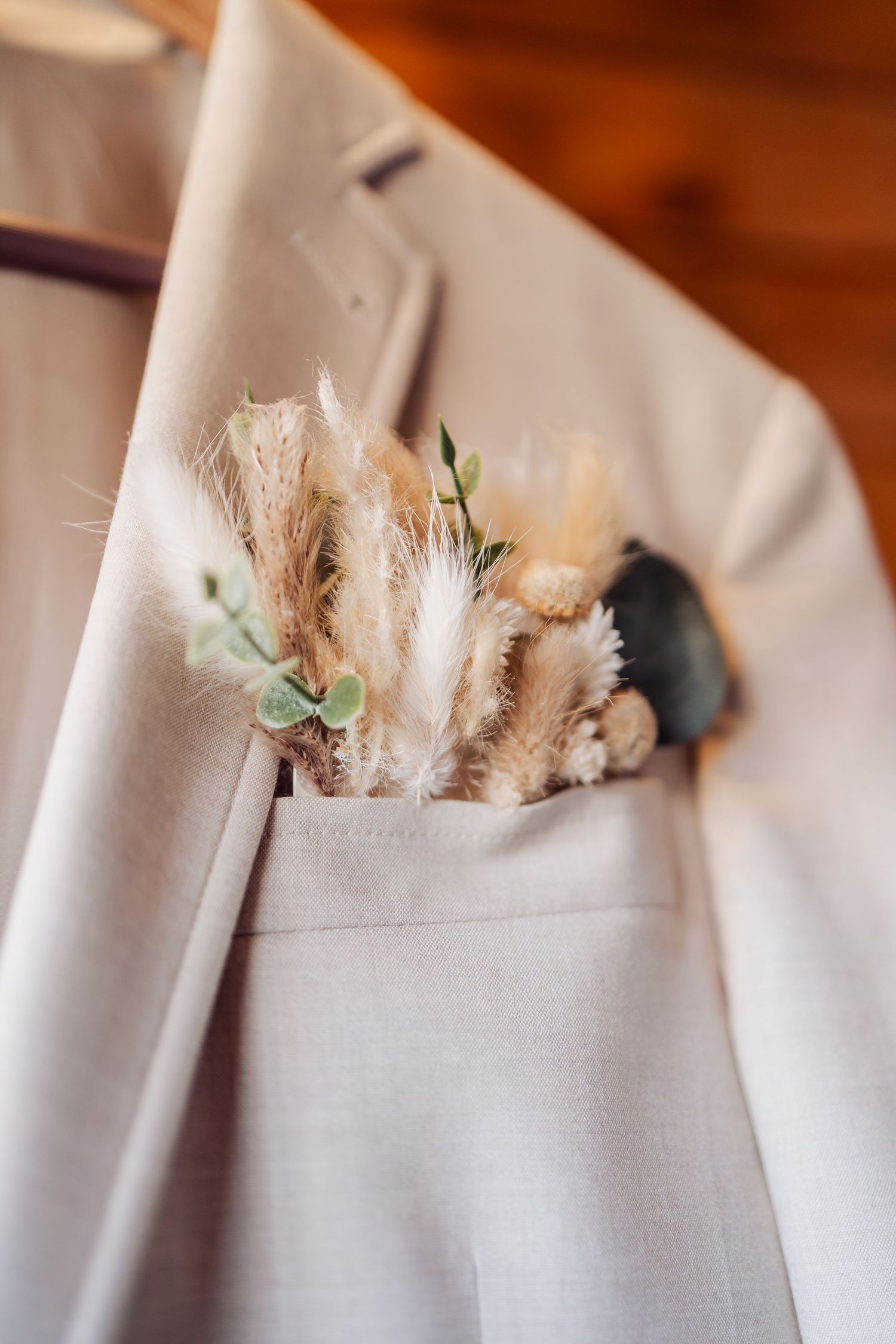 White linen napkin decorated with dried pampas grass flowers and greenery creates an elegant place setting detail.