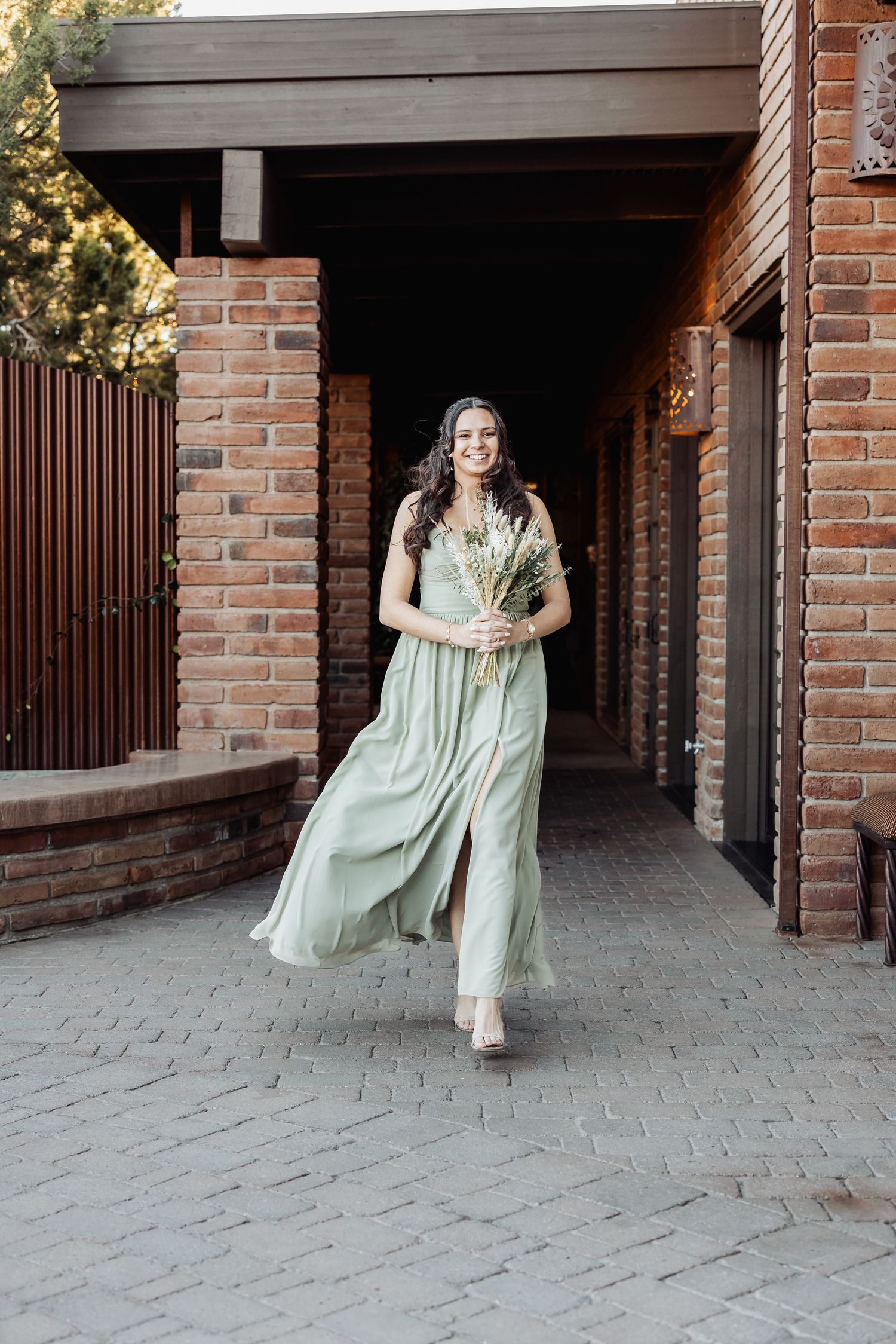 A four-panel sequence showing someone in a mint green dress twirling and dancing in front of a brick archway passage.