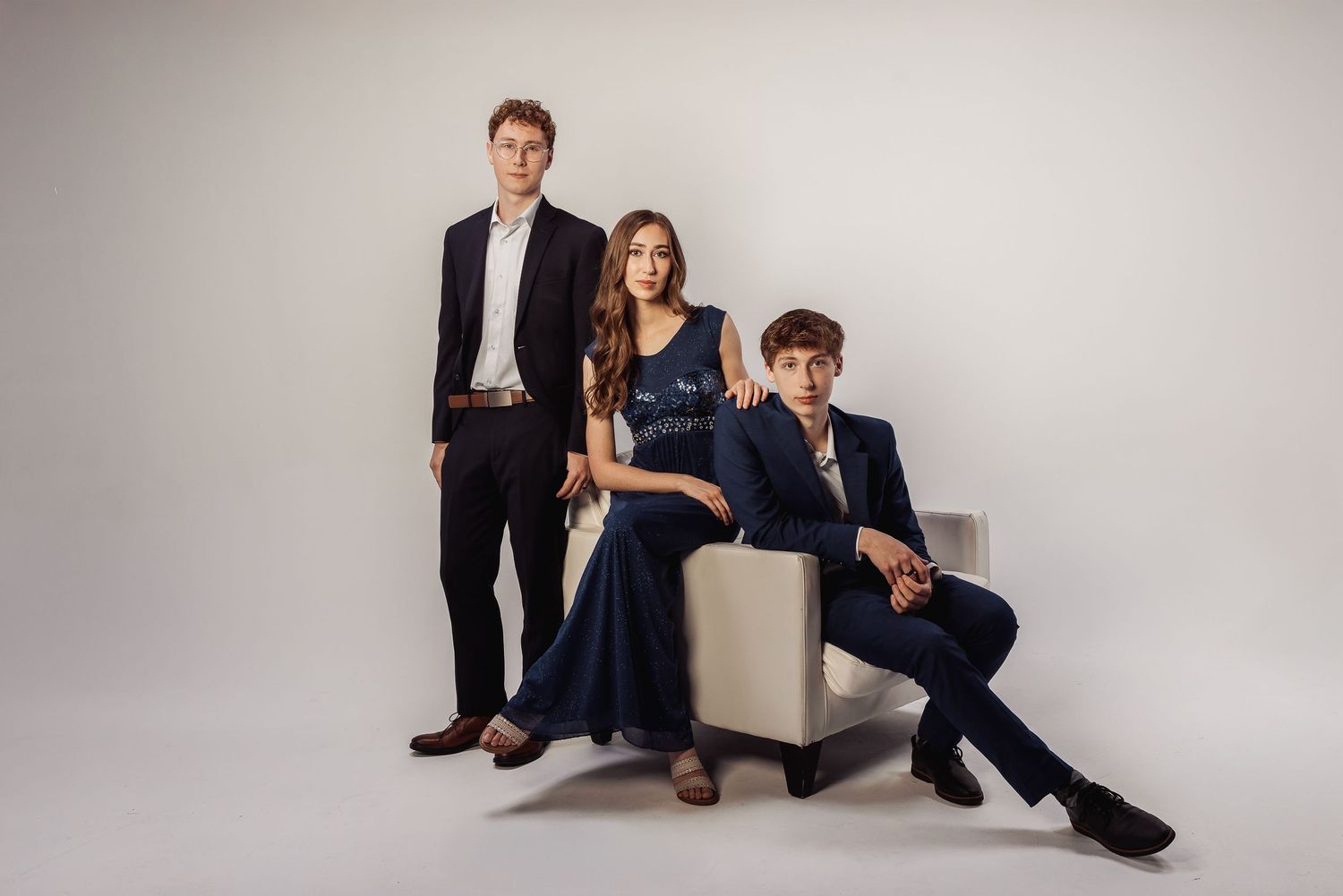 A group of people in casual business attire pose in various seated positions against a light gray studio backdrop.