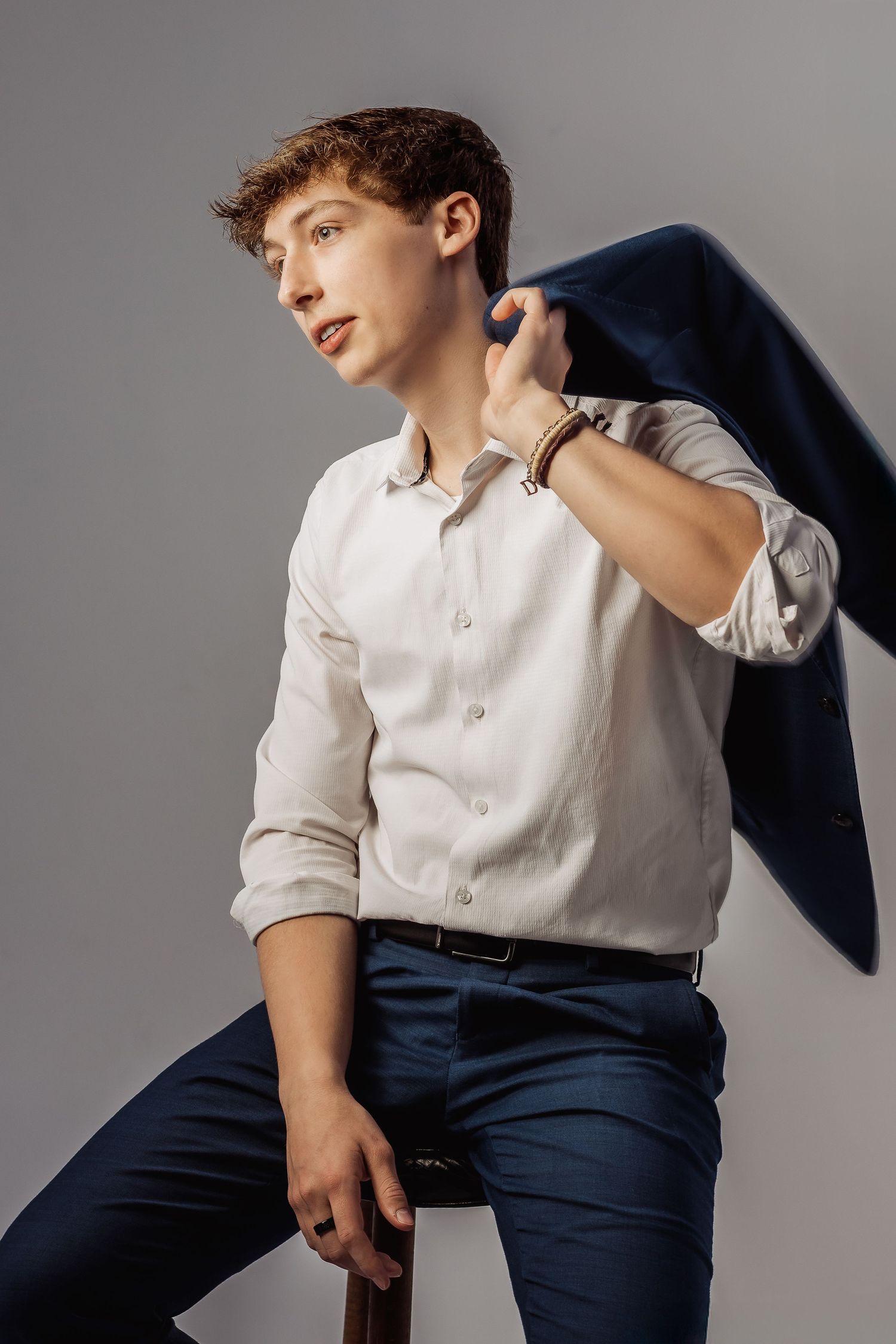 Professional studio portrait showing poses in a white shirt and navy blazer against a gray backdrop.