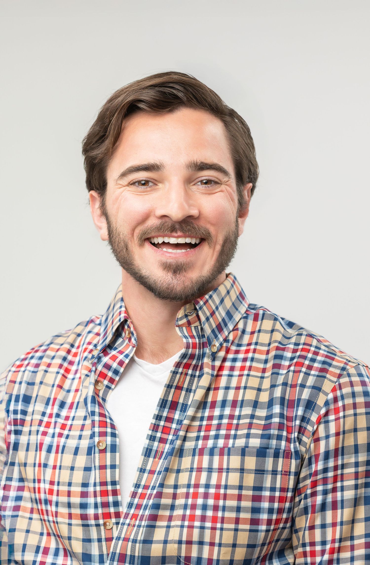 A sequence showing someone wearing a plaid button-up shirt expressing different emotions and smiling.
