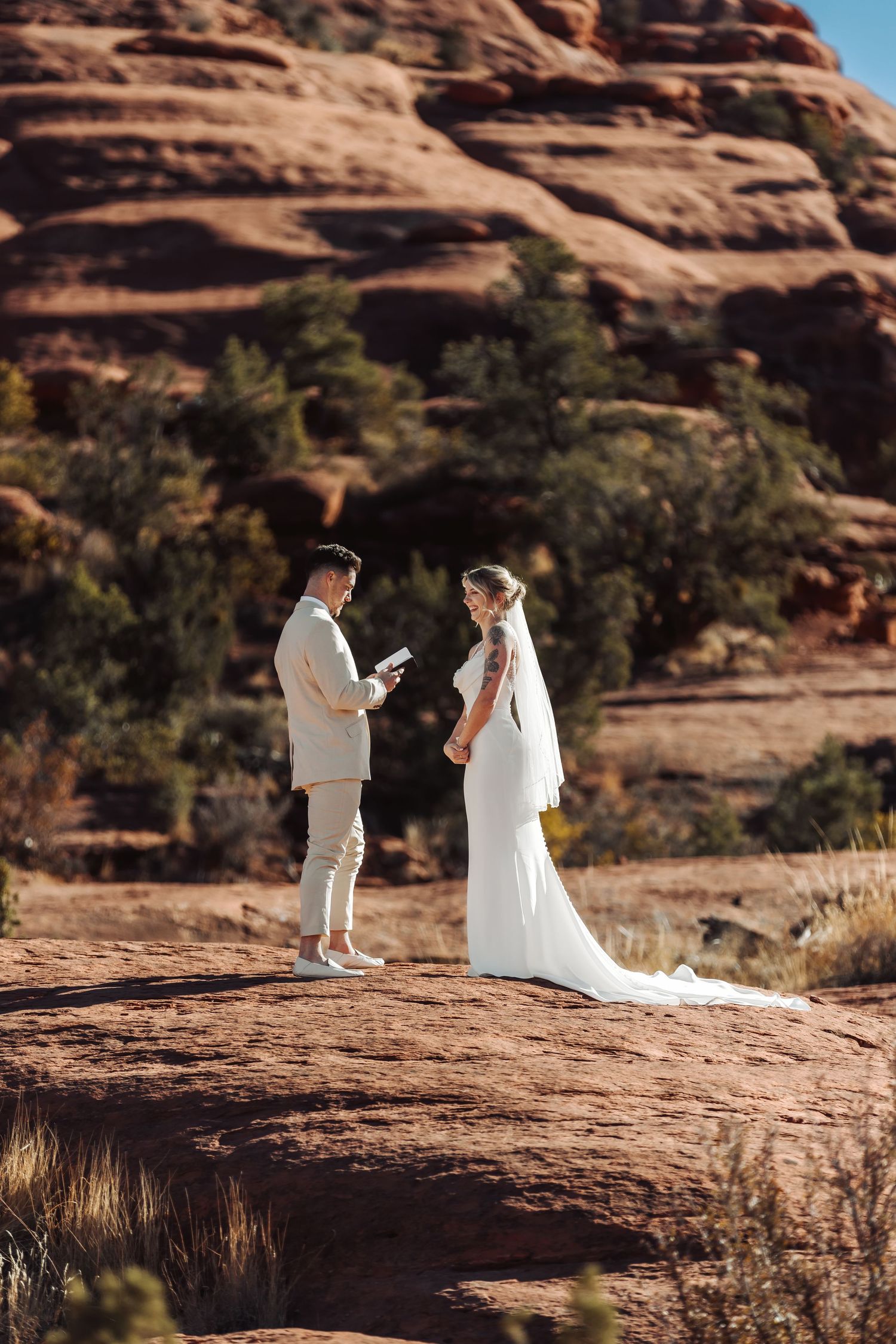 Couple exchanging vows during an intimate desert wedding ceremony against dramatic red rock formations.