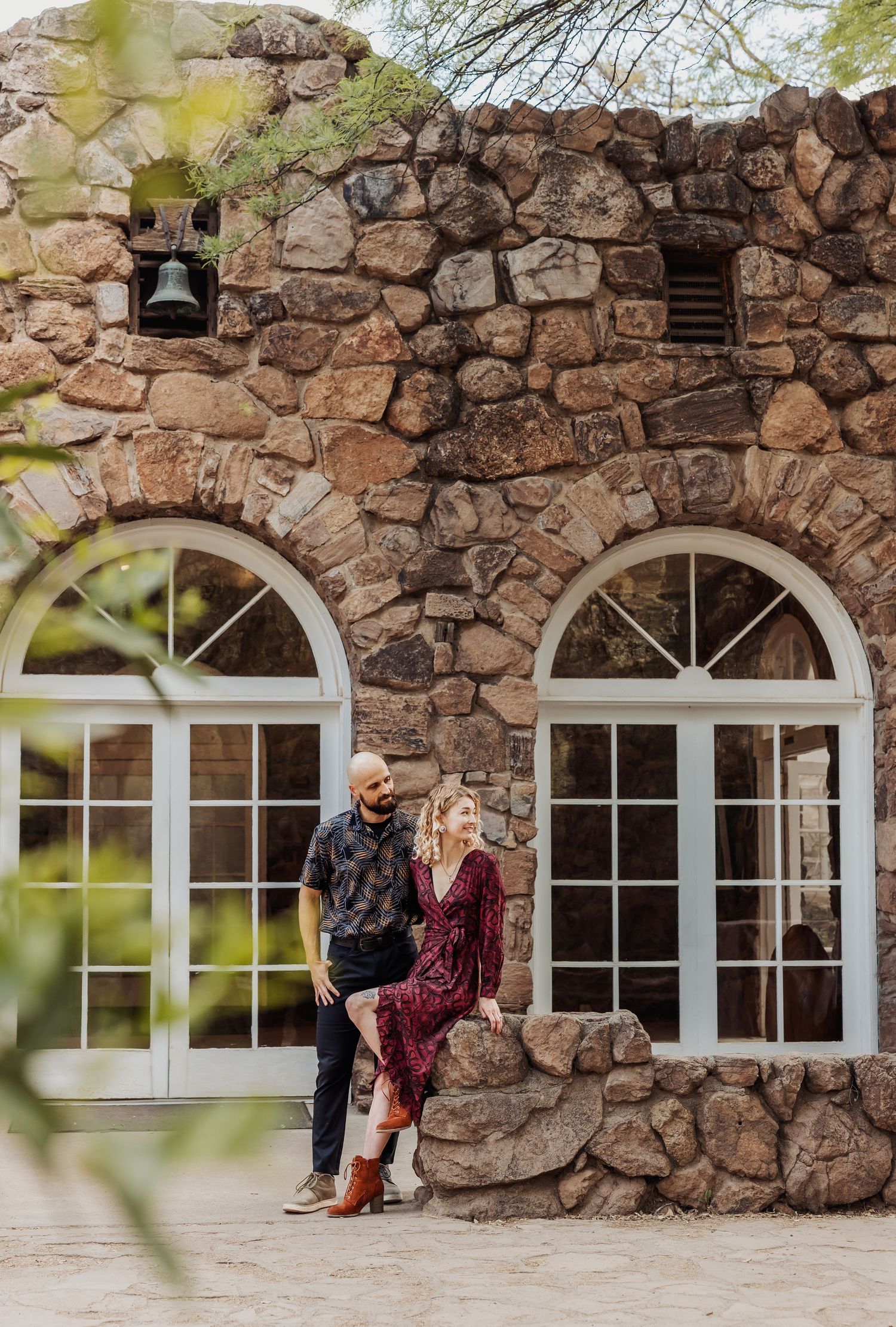 Stone building exterior with white arched windows and rustic stone wall architecture in romantic outdoor setting.