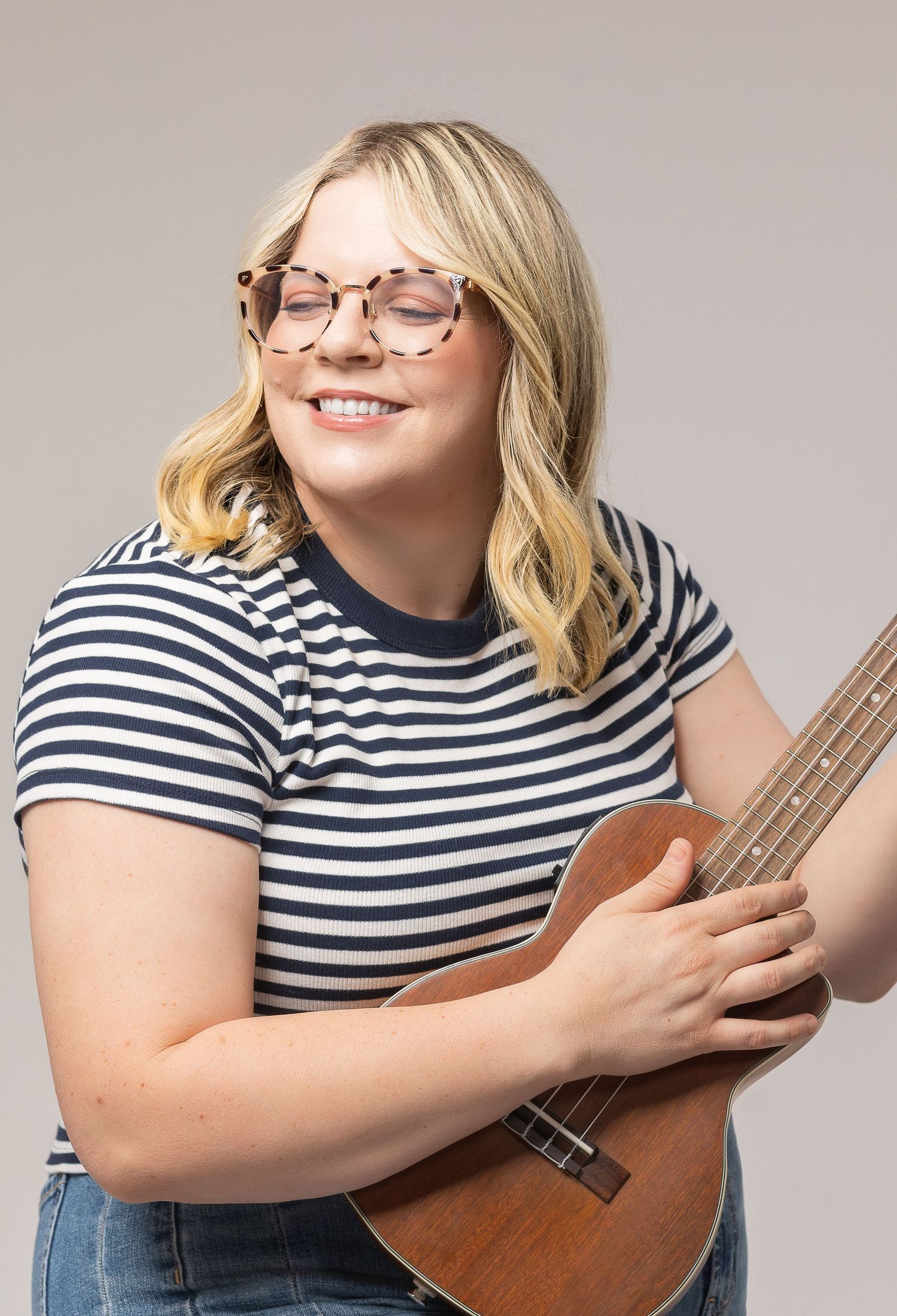 A person in a striped shirt and glasses holding a ukulele against a light background in multiple poses.