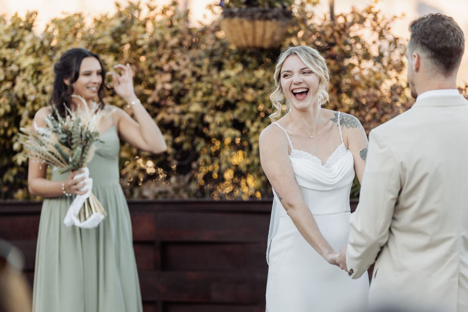Happy couple dancing and laughing together during their wedding celebration in a romantic outdoor setting at sunset.