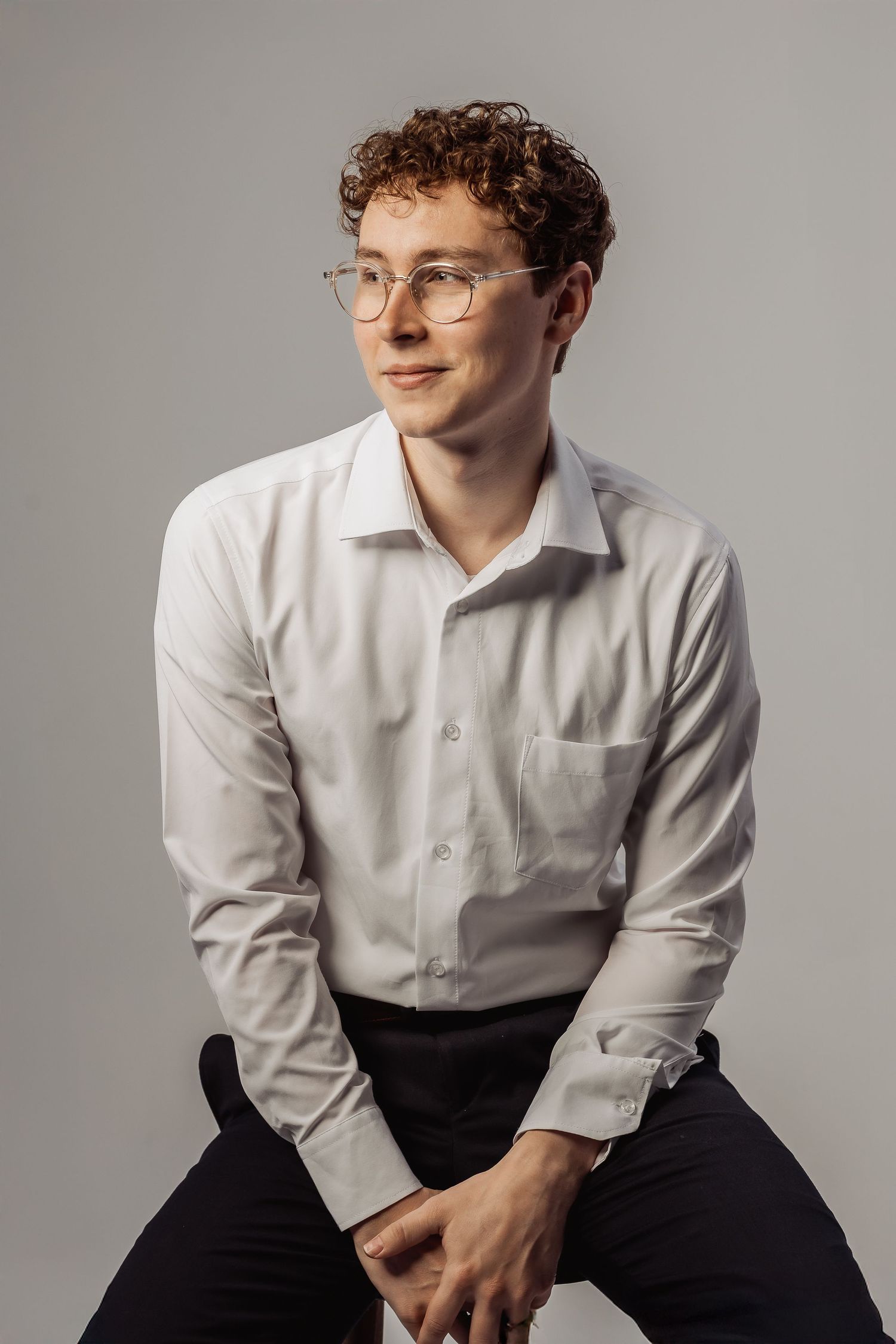 Studio photoshoot showcasing casual seated poses in business casual attire against gray background.