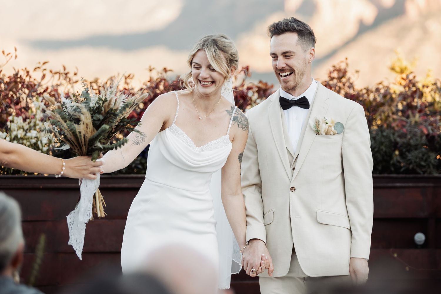 A happy couple in a joyful walking sequence in elegant white wedding attire in a sunset garden setting.