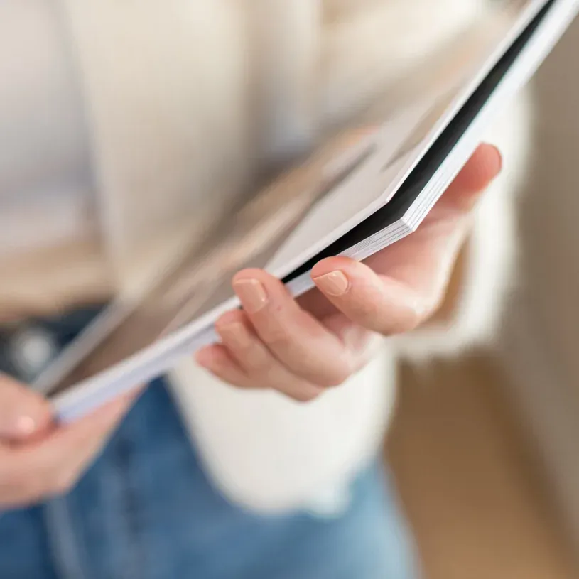 Close-up view of hands holding and reading from a document or paper with soft lighting and blurred background.