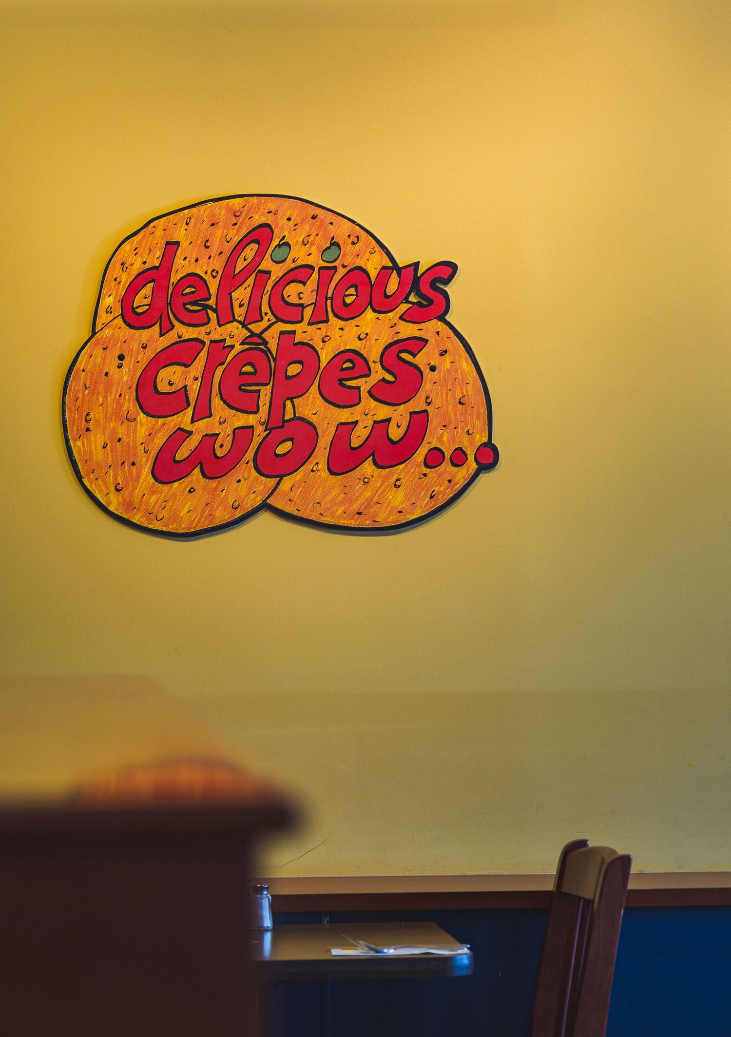 Bold yellow backdrop at Cora’s featuring a mix of typographic signs and cozy vibes in Victoria, Canada