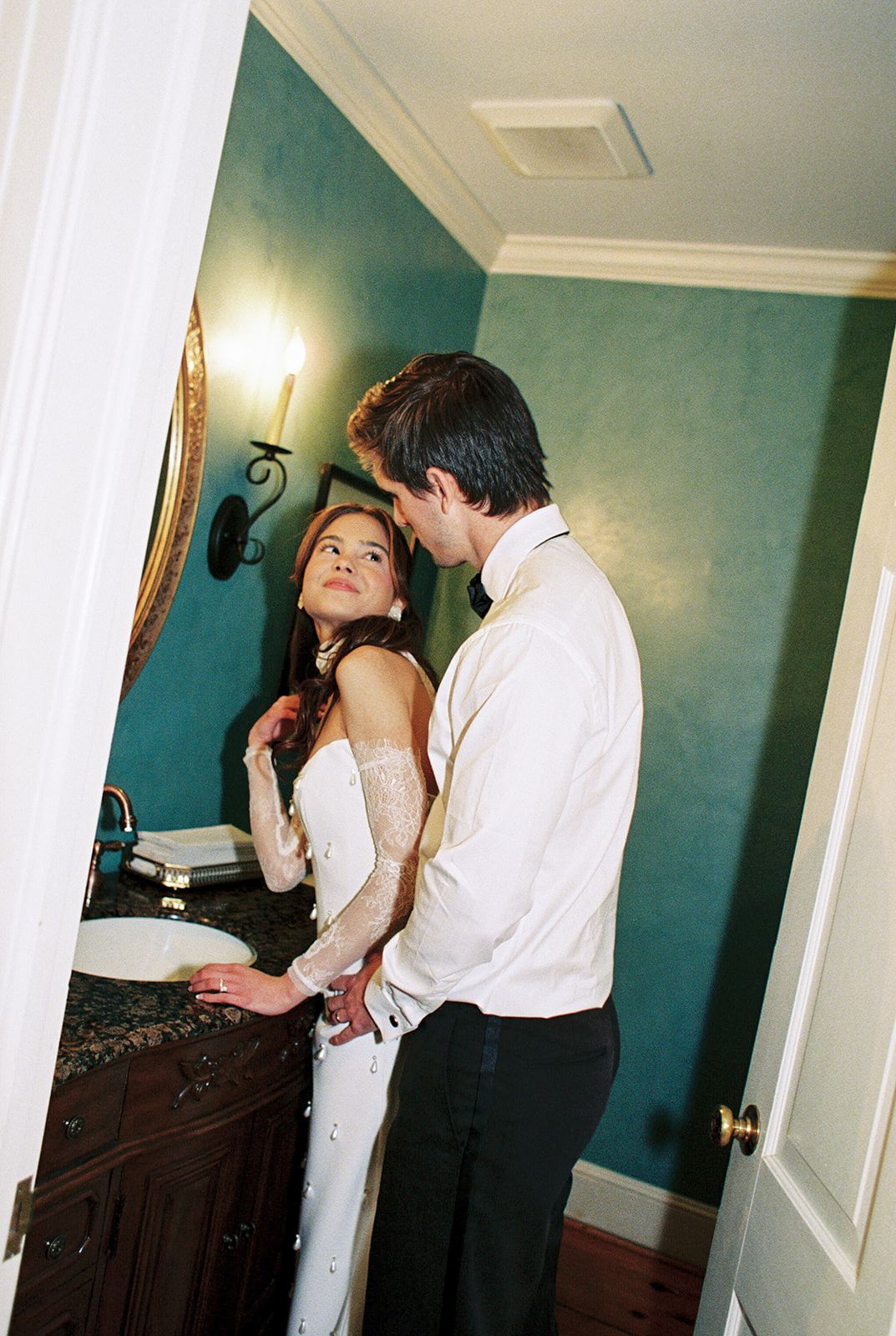 Series of photos showing a romantic couple in formal attire dancing and embracing in a room with teal walls.