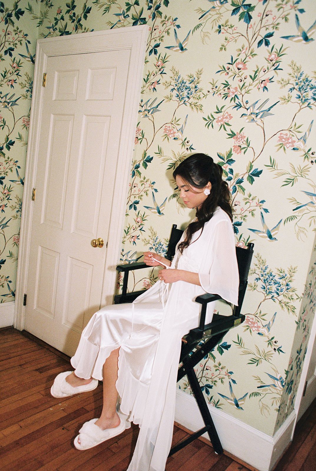 Four photo sequence showing someone in a white robe getting ready in a room with floral wallpaper and hardwood floors.