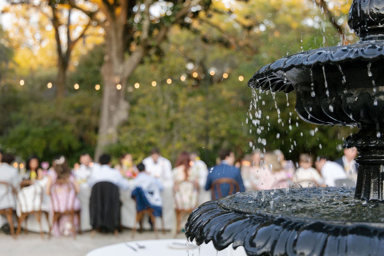 A group wearing white clothing stands in a wooded outdoor setting during what appears to be a ceremonial gathering.