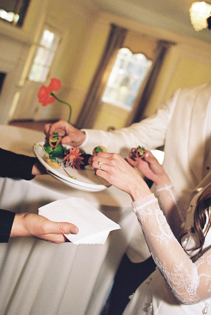 Close-up of hands exchanging delicate pink roses during a formal celebration or ceremony.