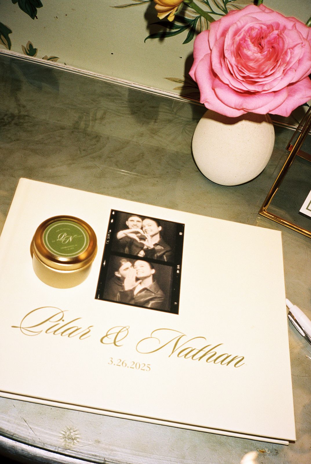 Wedding invitation cards with pink roses and gold calligraphy displayed on a gray surface.