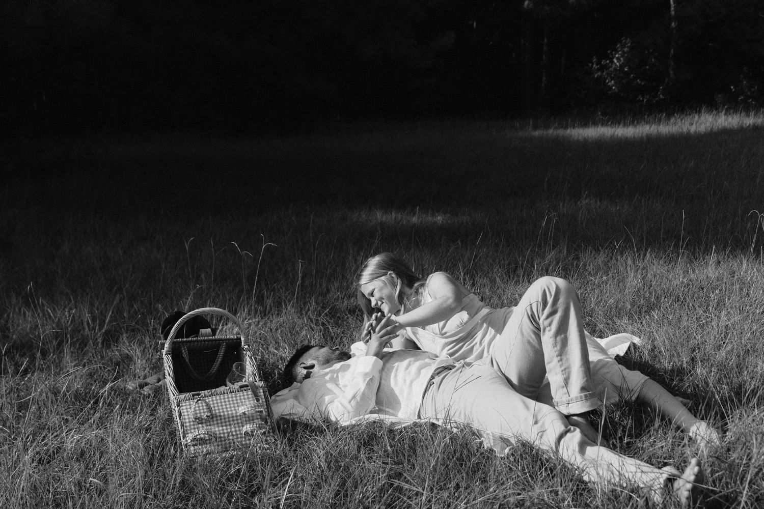 Black and white photograph showing laid back cattle resting in a grassy field on a sunny day.