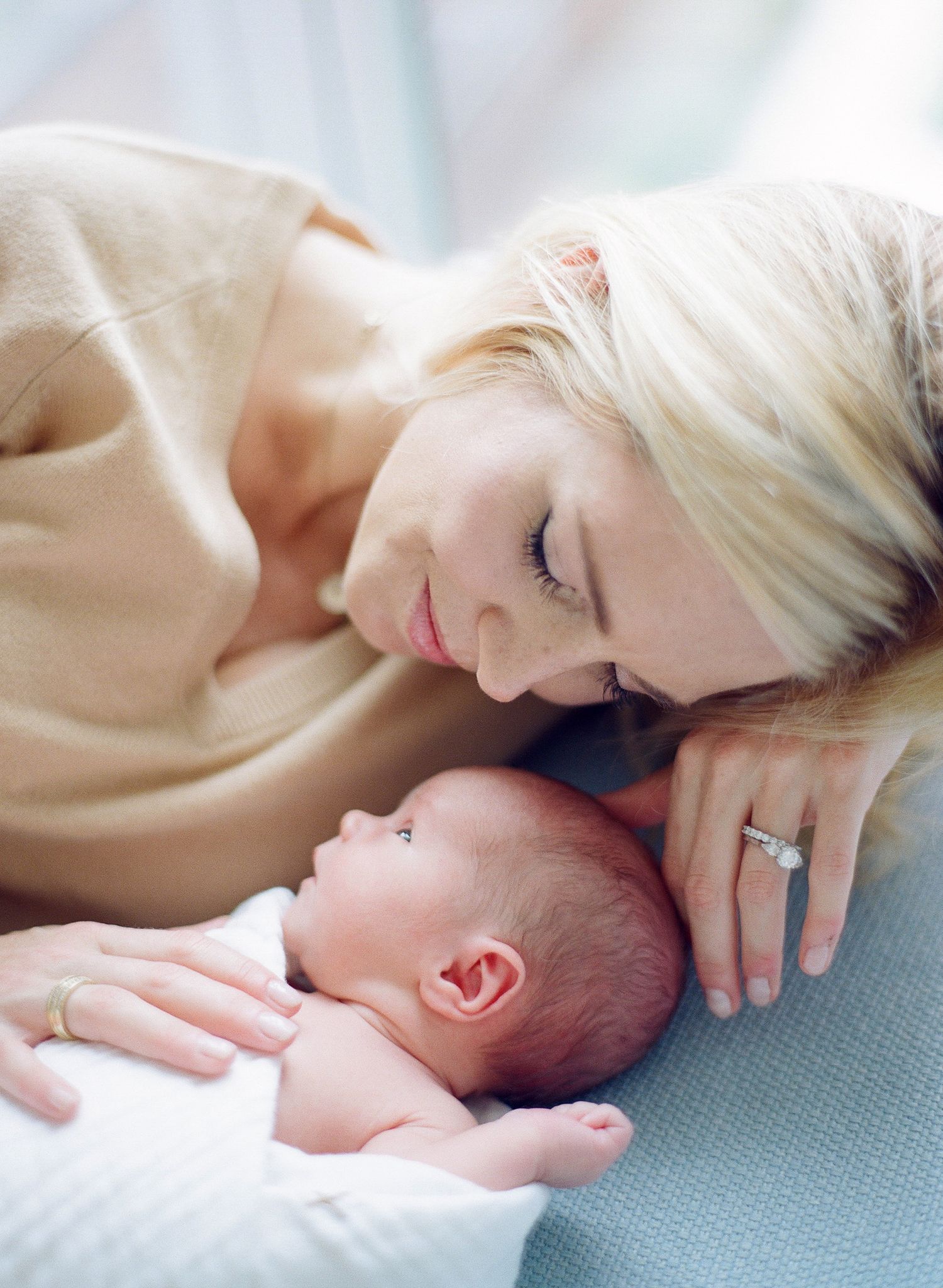Close-up tender moment between parent and newborn baby lying together.