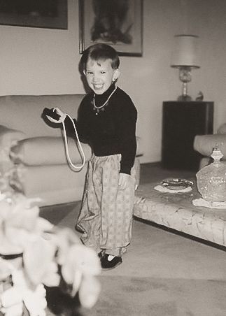 Vintage black and white photograph showing someone sitting on a floor with blurred white objects visible in the foreground.