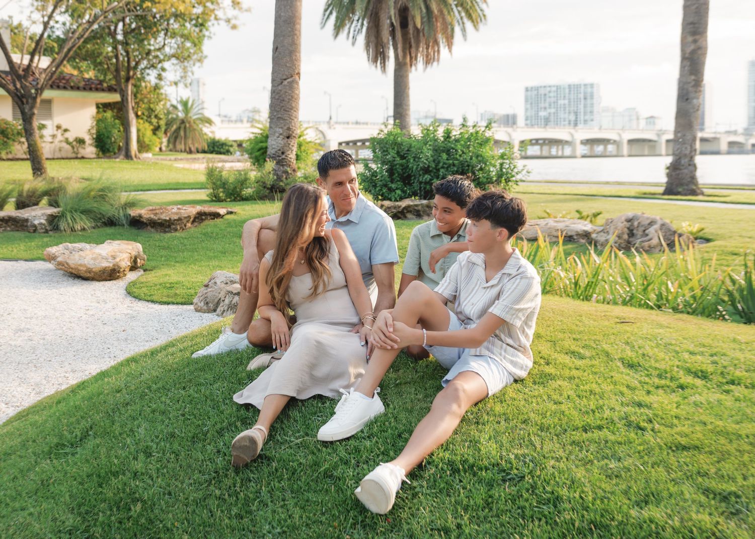 Group relaxing on grass under palm trees in park setting during golden hour.