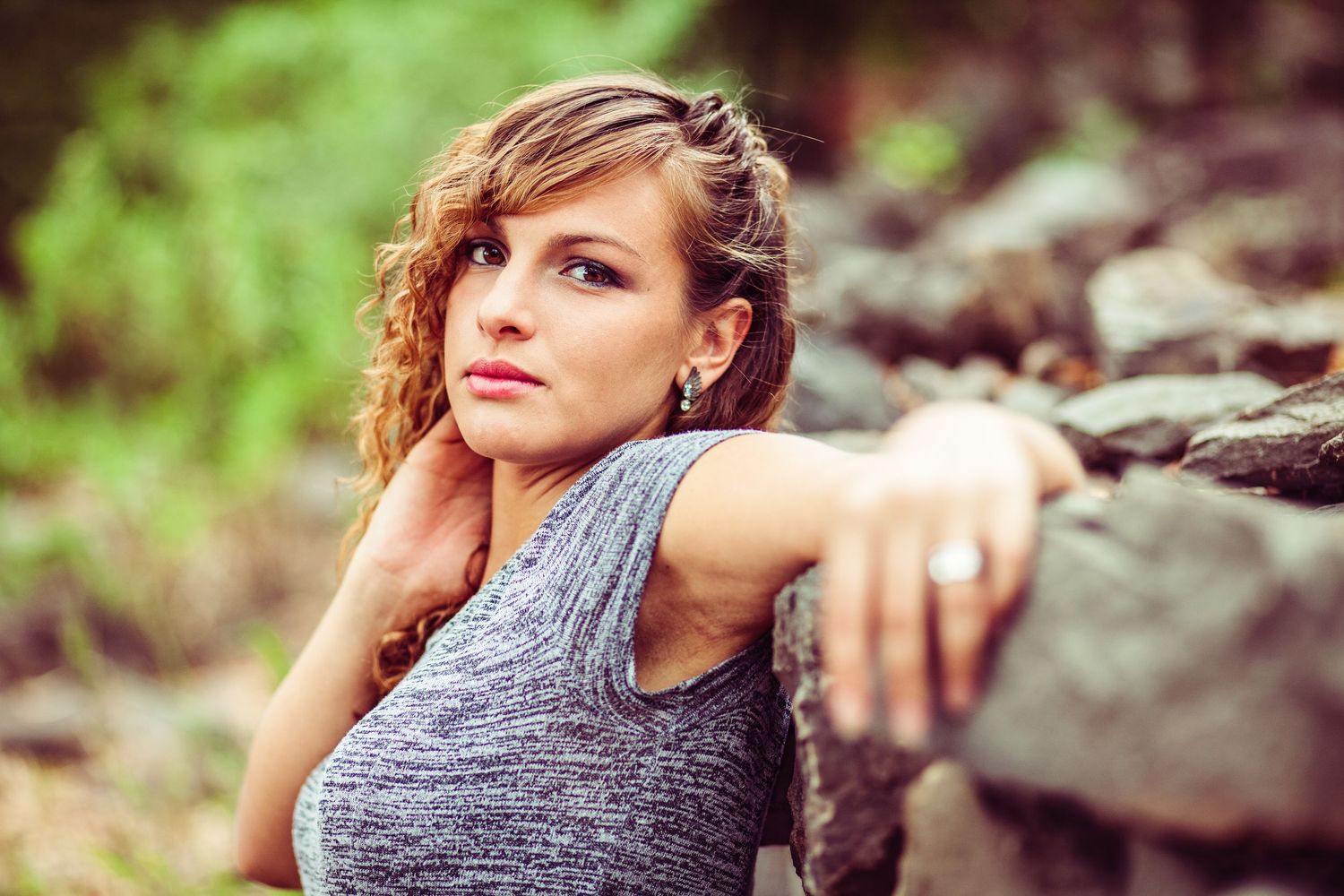 Outdoor portrait against rocky backdrop with model wearing grey athletic tank top.