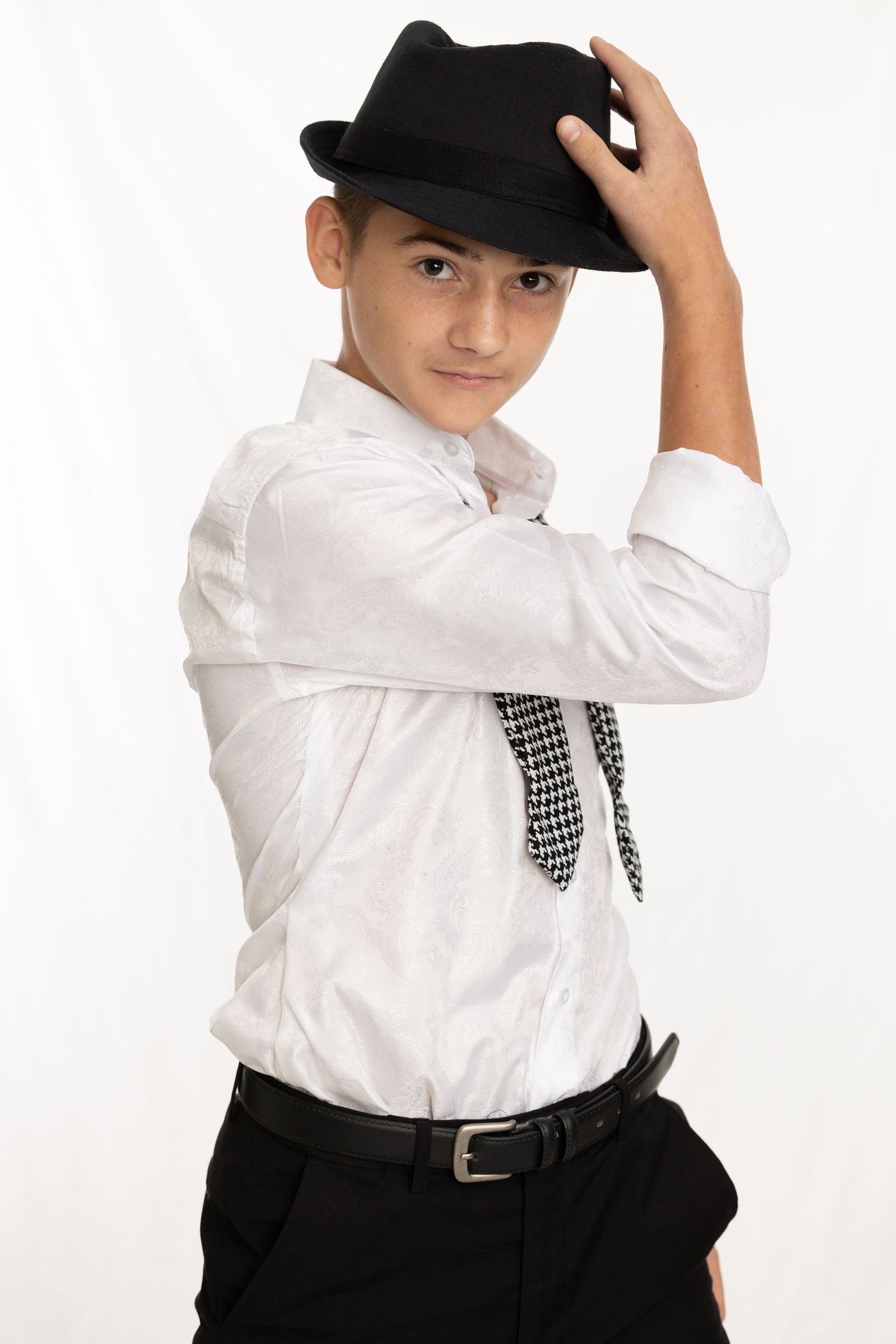 A performer in a classic black and white outfit with black fedora hat poses in a stylish dance stance against white background.