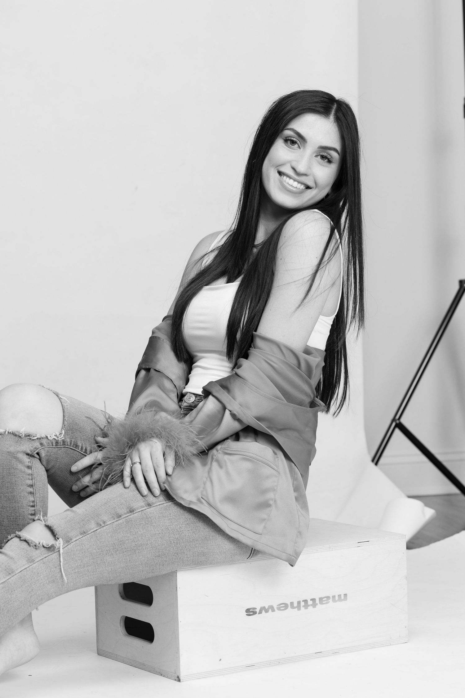 Black and white portrait of someone in casual attire sitting relaxed on a Samsung branded box.