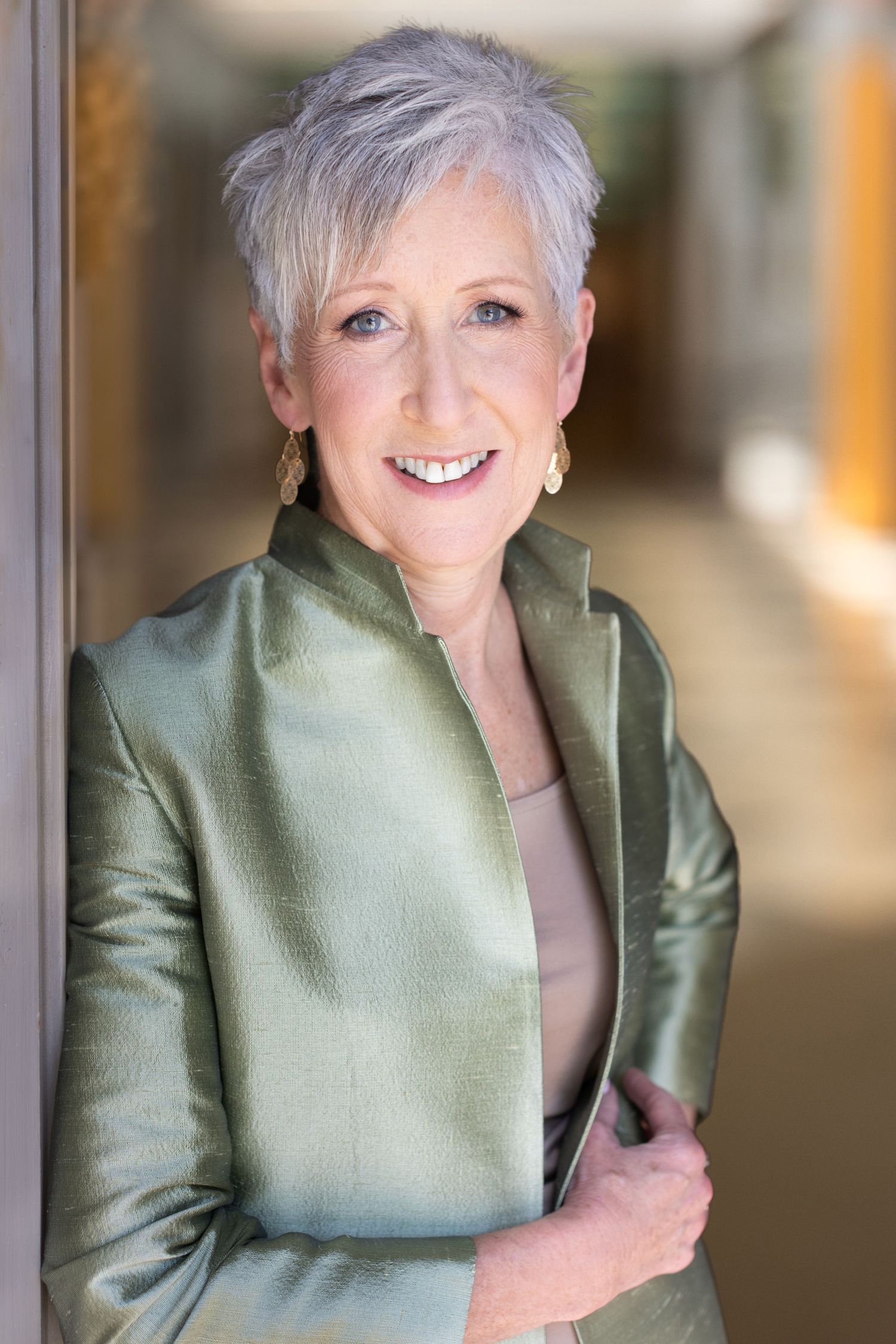 A person with silver-grey hair wearing a sage green jacket is shown in a series of five photos.