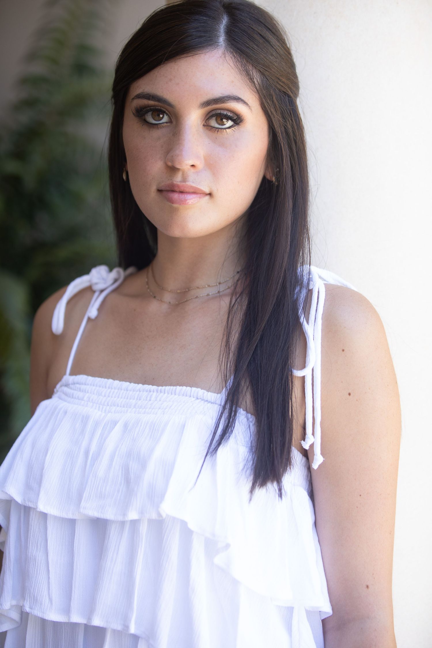 A series of portraits showing someone wearing a white ruffled top in an outdoor setting with natural lighting and greenery.
